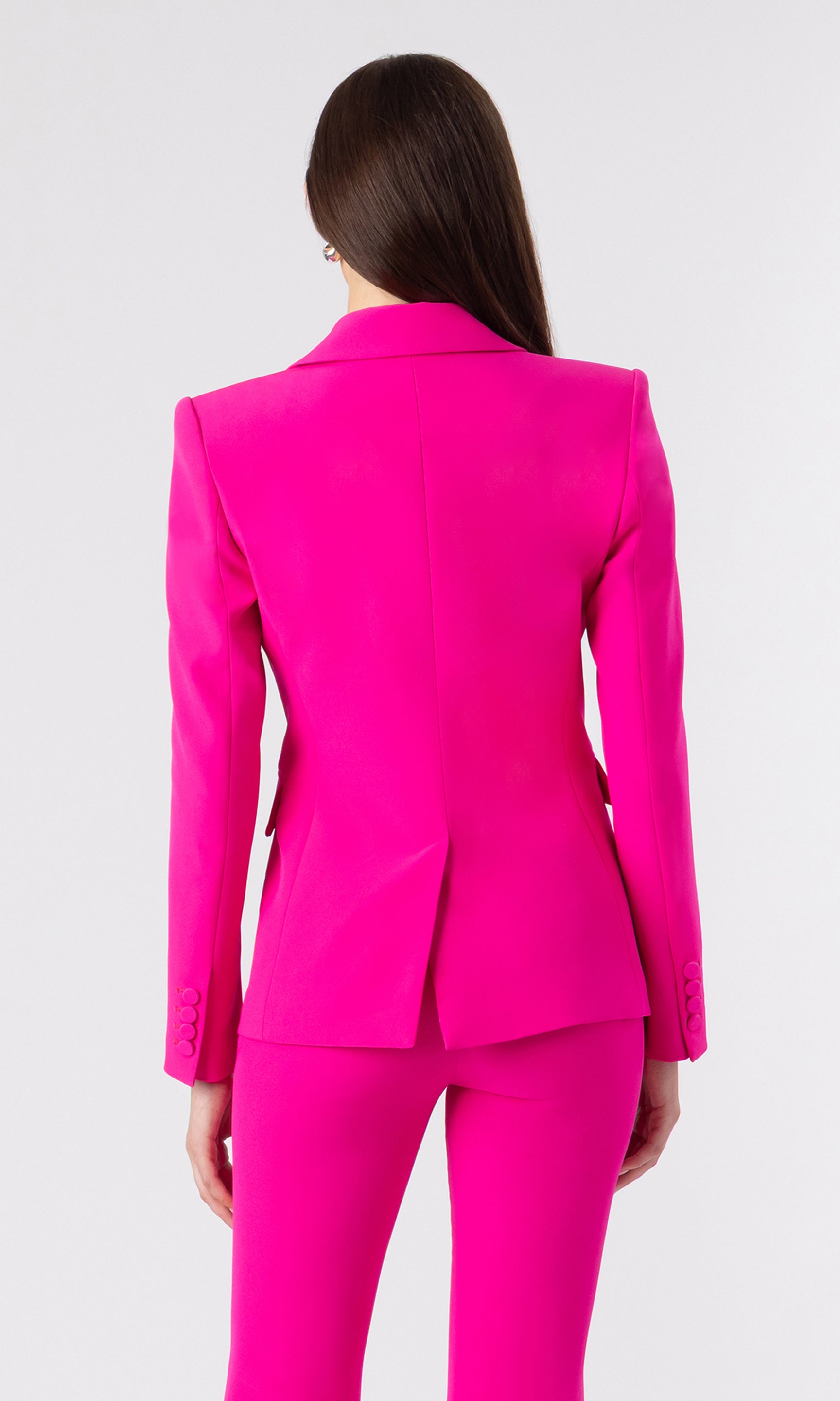 back image of model wearing a hot pink blazer with matching hot pink trousers 