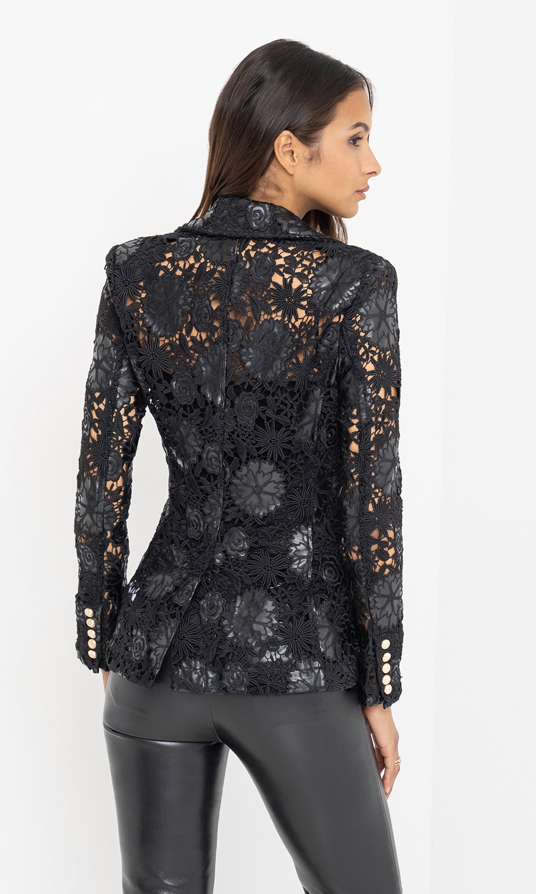 From the rear, the model reveals the full guipure back panel, showcasing the blazer’s unlined lace design and fitted silhouette.