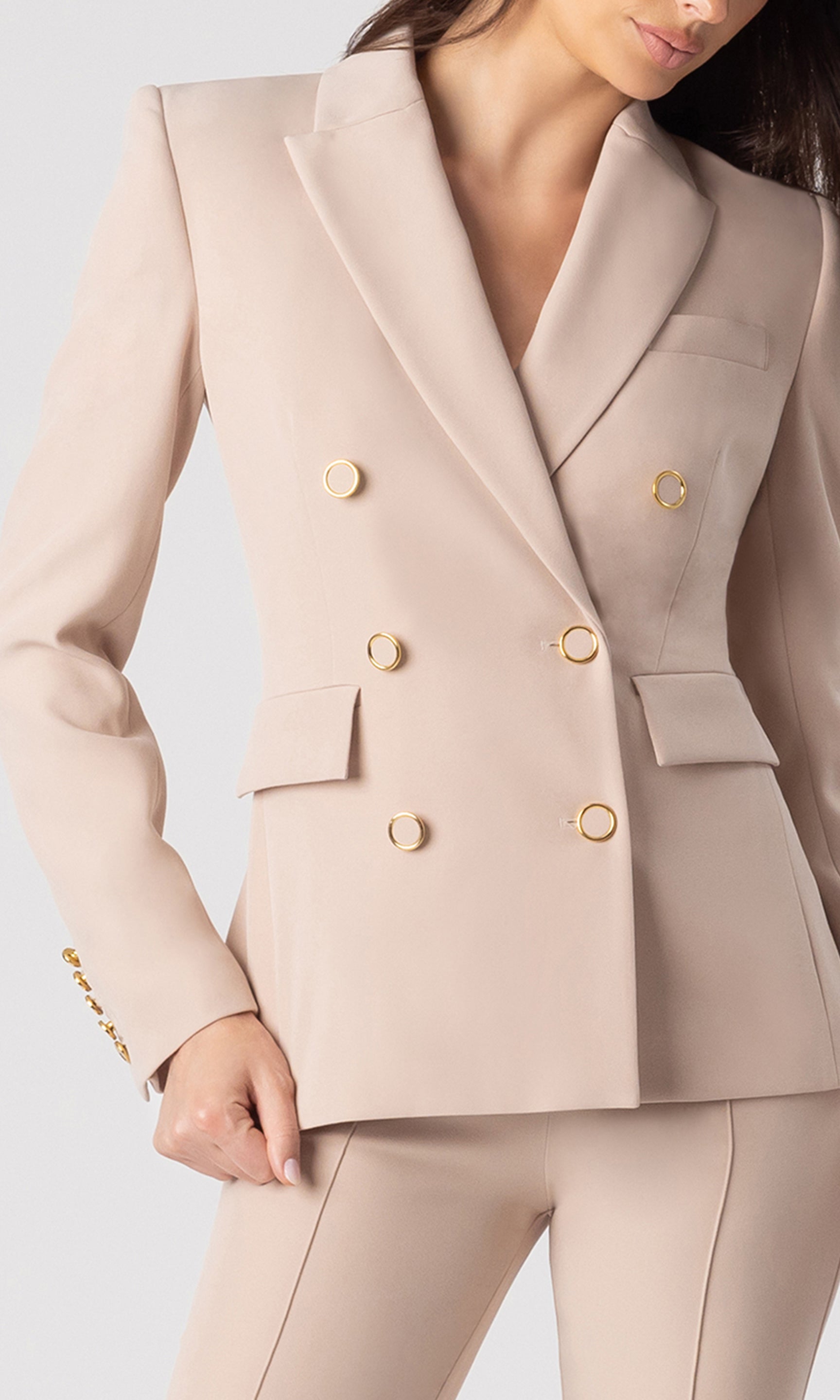 zoomed in detail image of model wearing the Arielle crepe blazer in latte with matching latte trousers, showcasing the structure of the blazer and gold rimmed buttons on the front