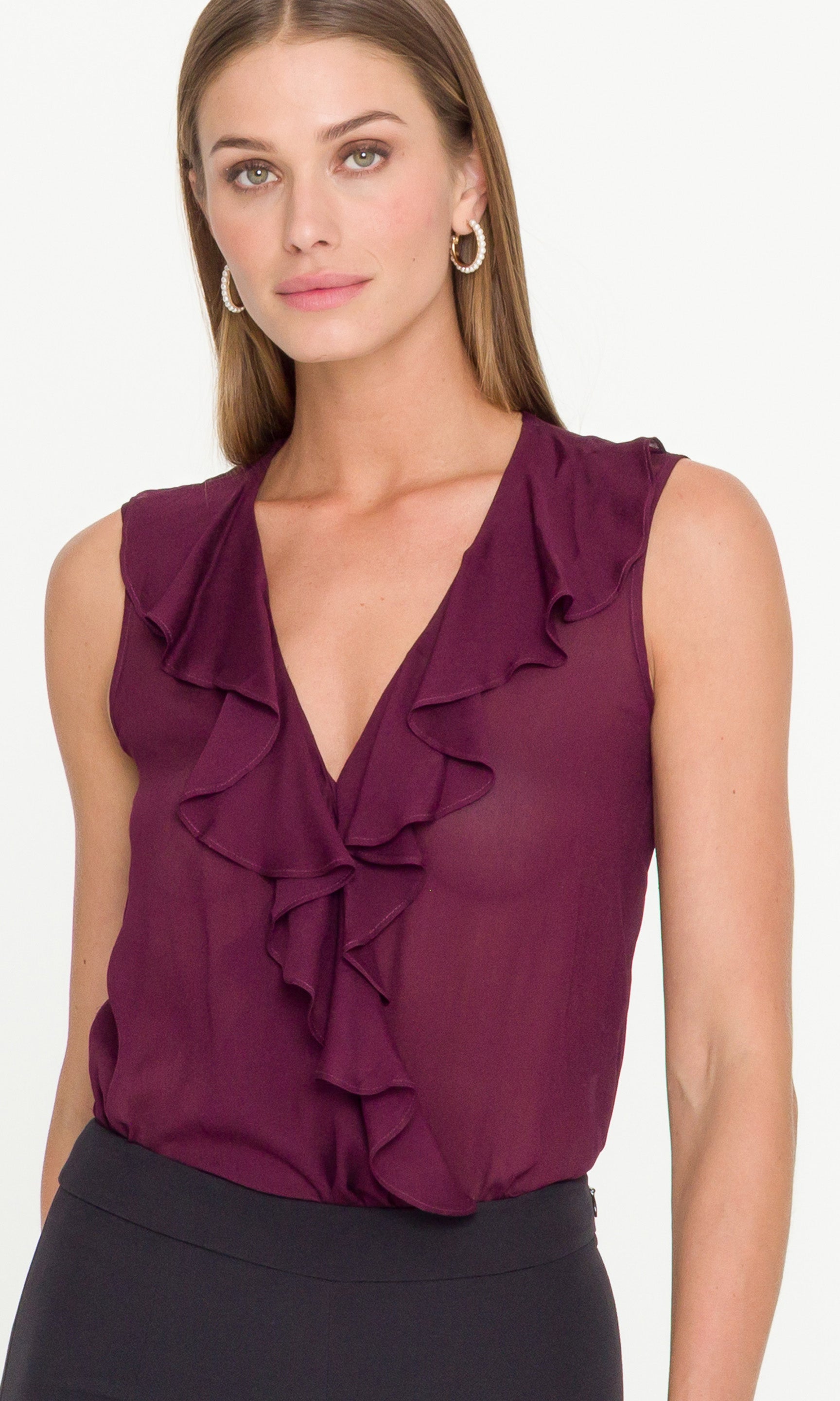 Woman wearing a purple ruffled blouse on a white background showing the ruffle detail 