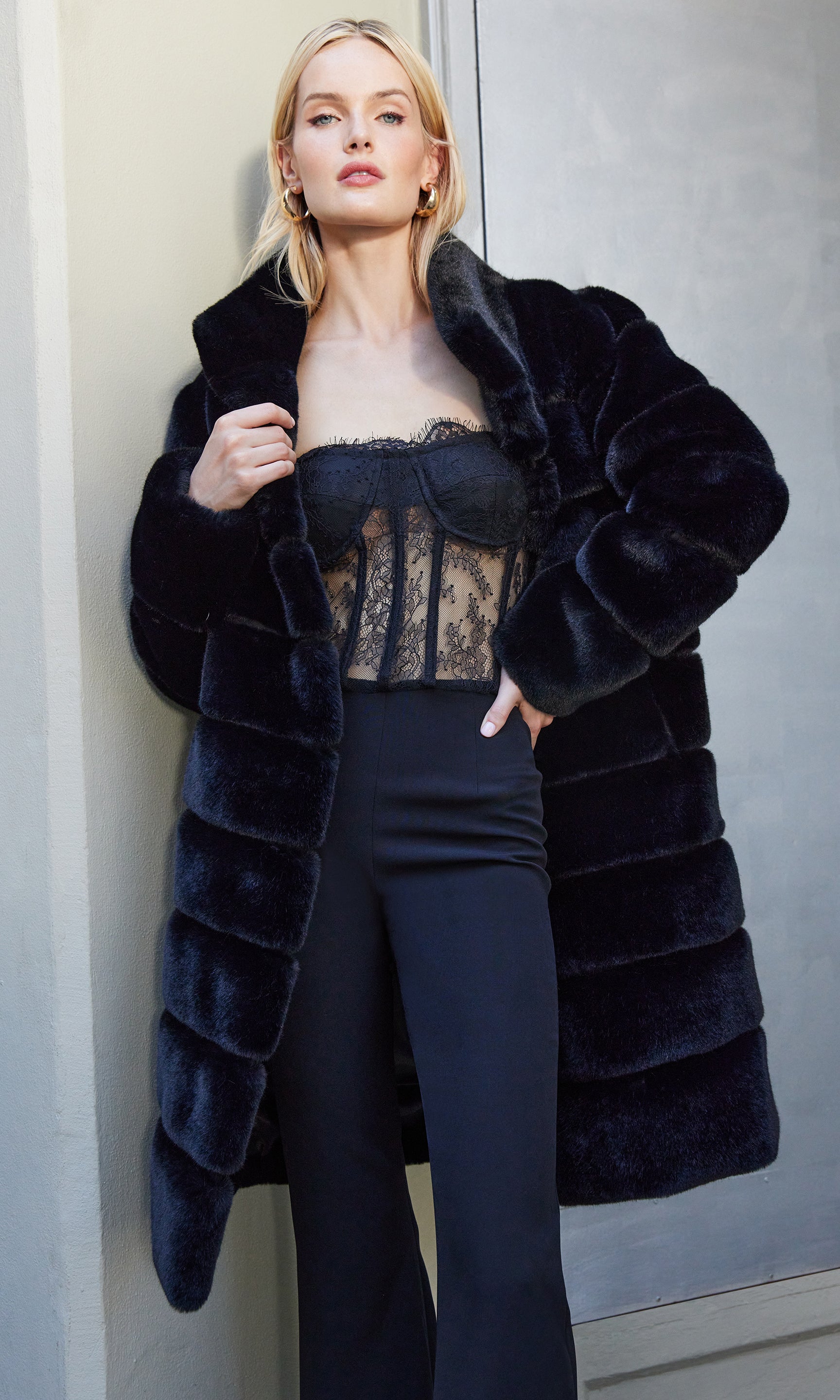 Woman wearing a dark blue fur coat with a plain background
