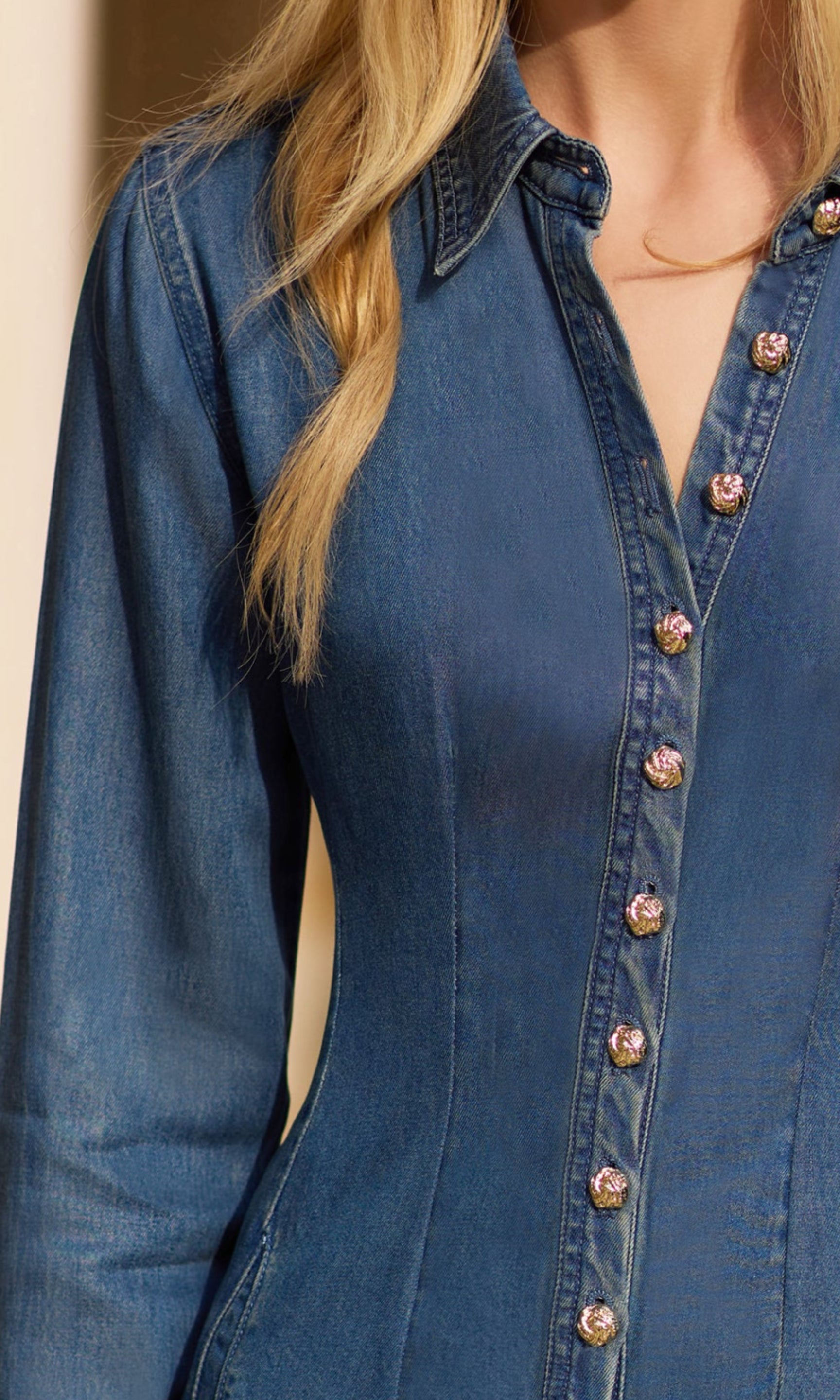 zoomed in image of model outdoors posing in front of a house wearing the Clemente tencel denim dress in a denim blue wash, showcasing the gold buttons down the front of the dress