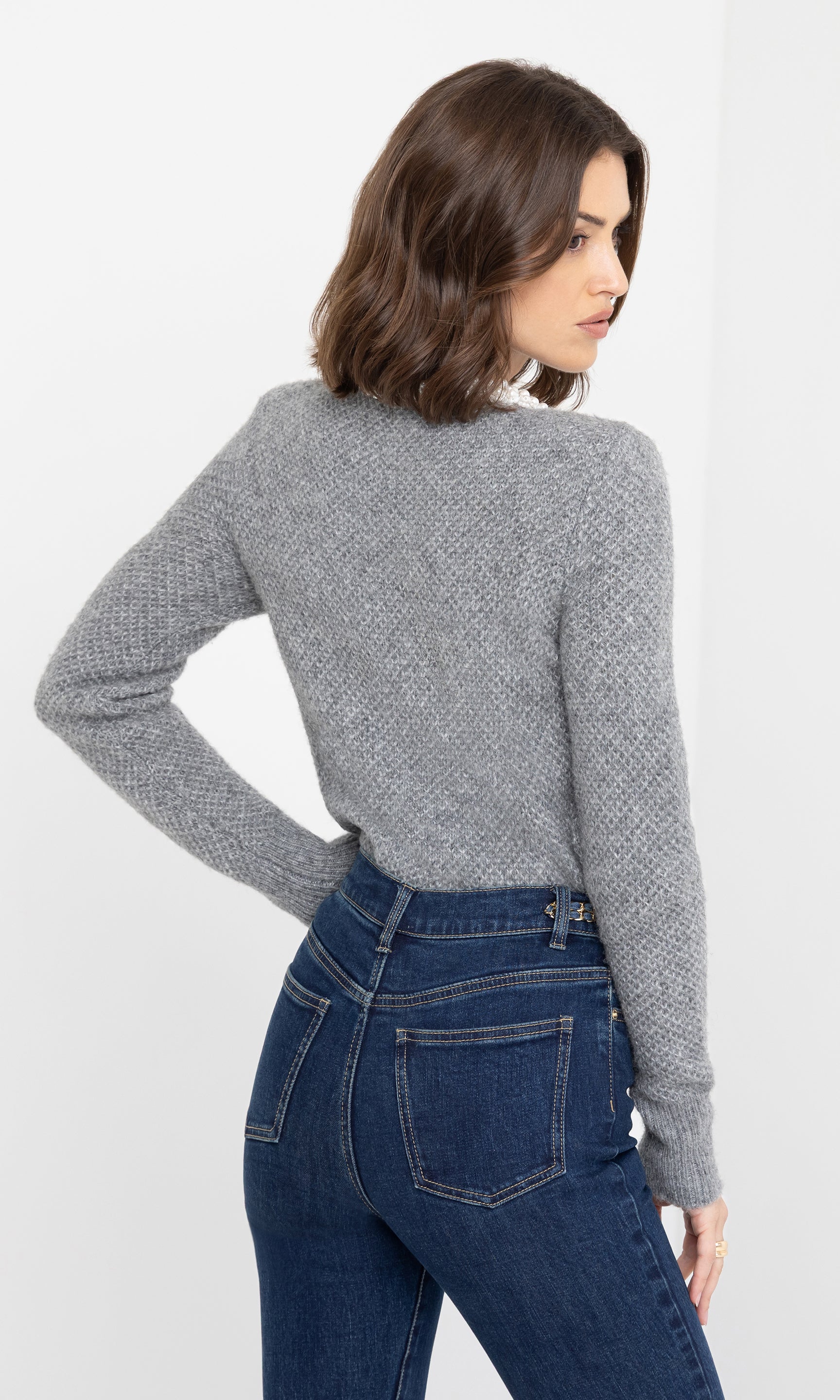 Rear angled view of the Clove Cardigan in grey, showing its fitted silhouette and pearl button accents.