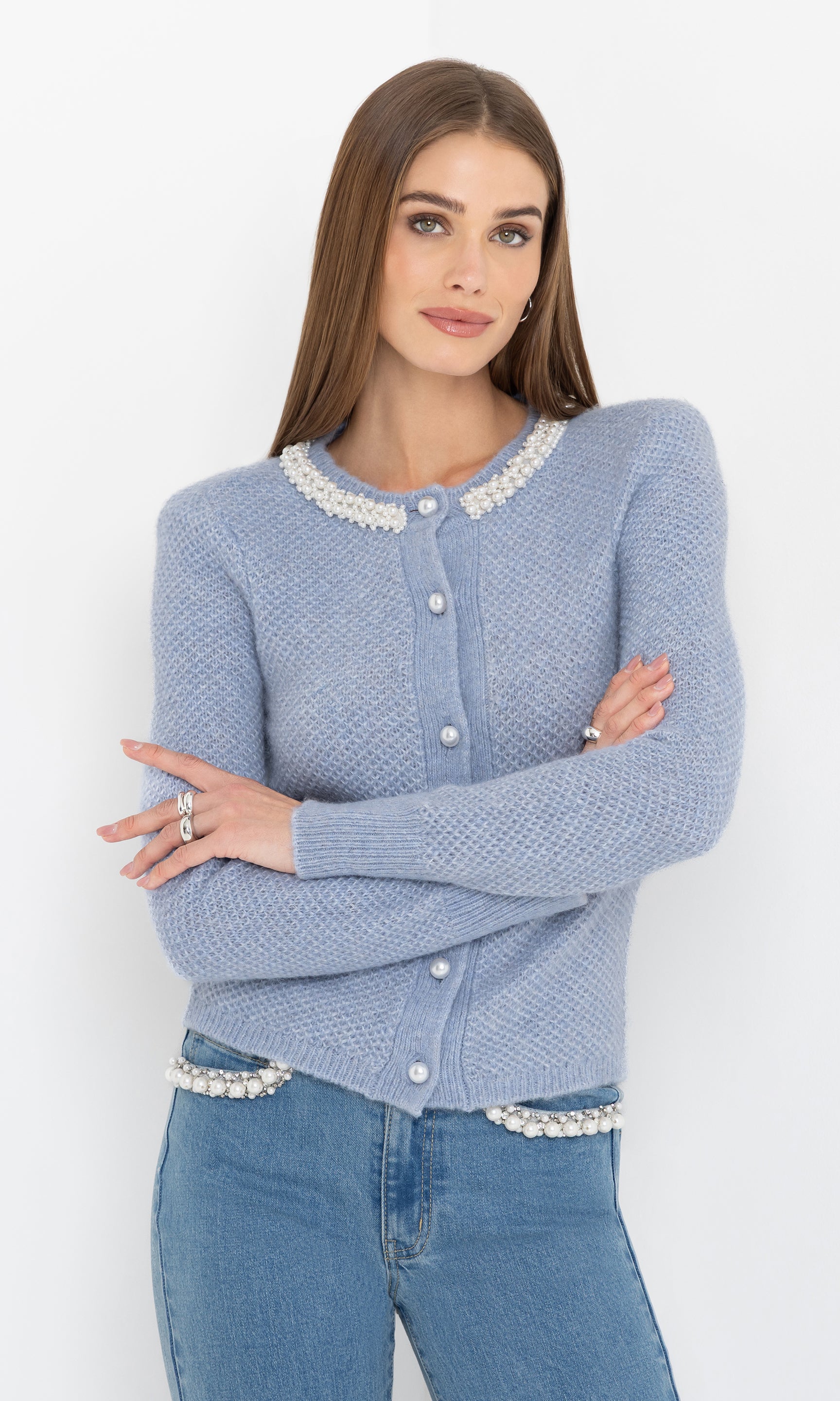 Front view of the Clove Cardigan in soft blue, styled with pearl trim and worn over light blue jeans.