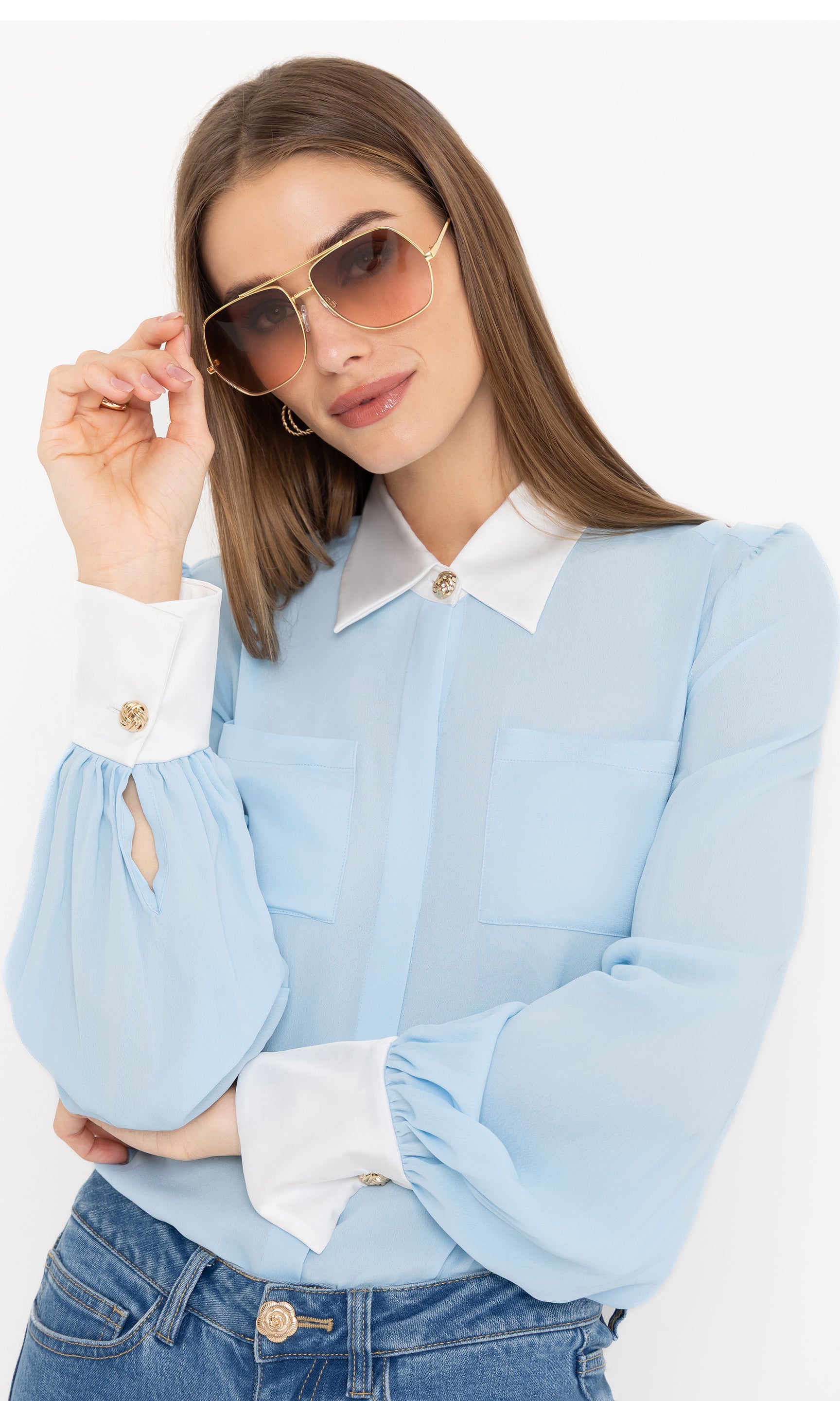 Stylish front view of the Denise Georgette Combo Blouse in light blue, paired with jeans and accessorized with sunglasses.