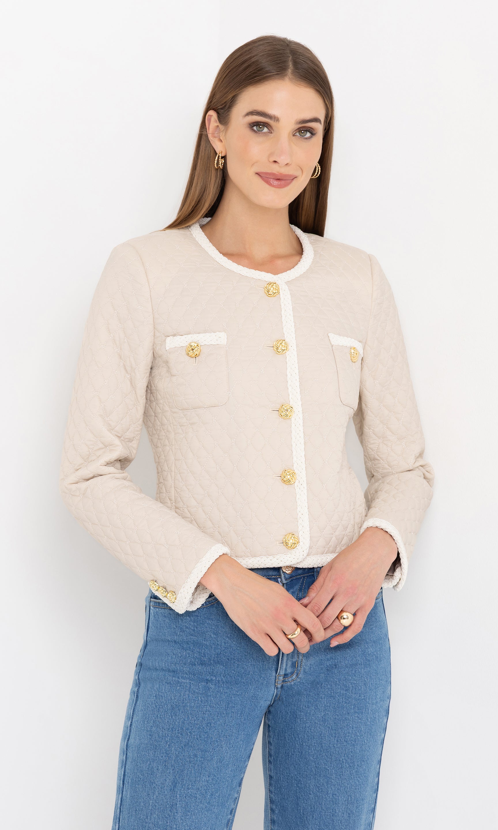 Smiling in a front view pose, the model showcases the cream Everie quilted jacket styled with blue jeans.
