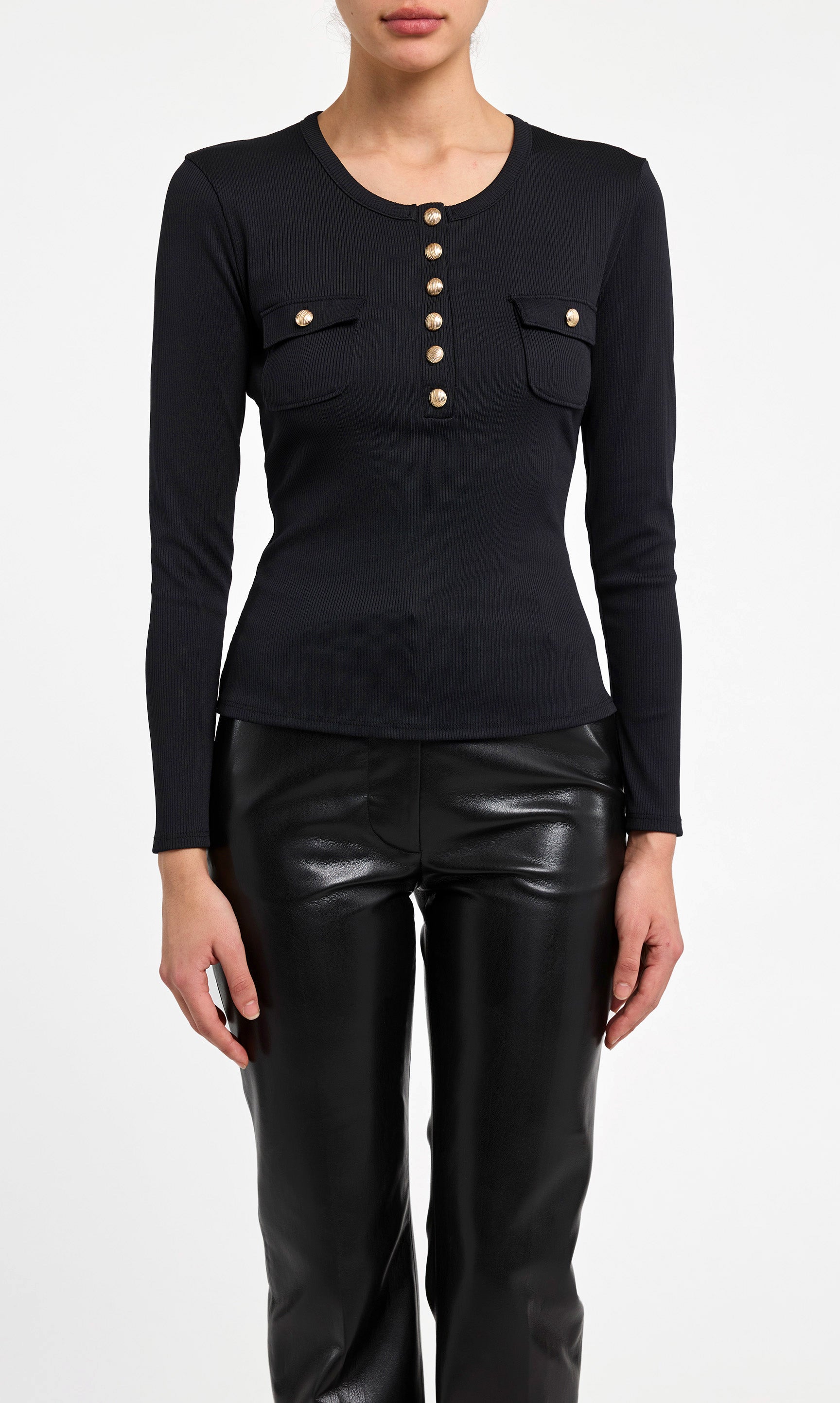 Black long-sleeve top with button details and black leather pants on a white background