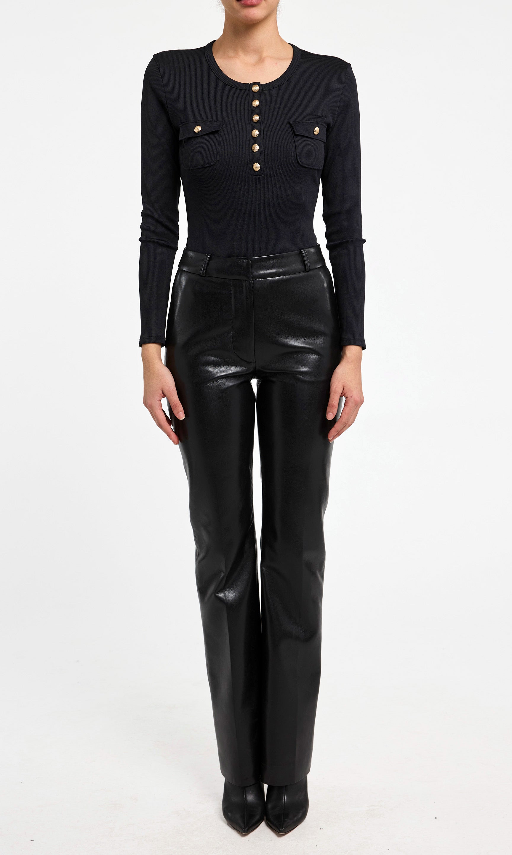 Person wearing a black long-sleeve top and black leather pants on a white background
