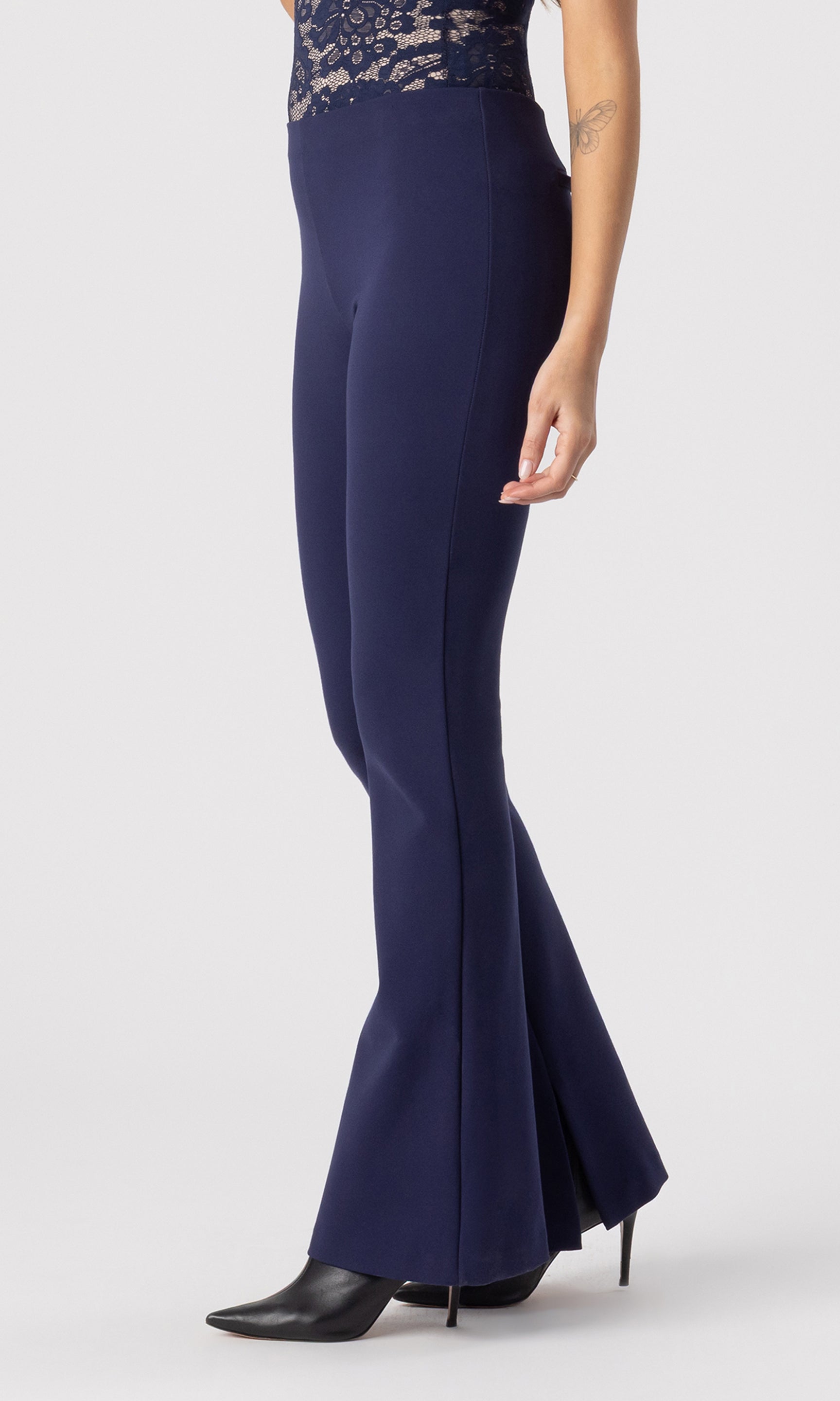 cropped side view image of model wearing the Murray Ponte Leggings in navy, paired with a navy/beige lace bodysuit and black heeled booties