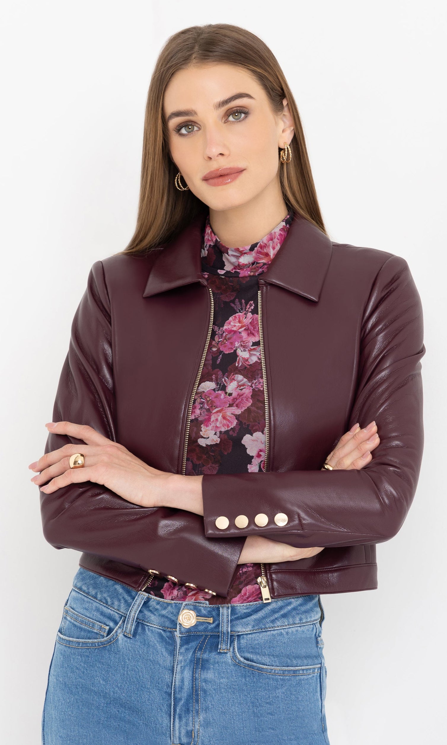 Woman wearing a cabernet vegan leather jacket over a floral shirt with a white background