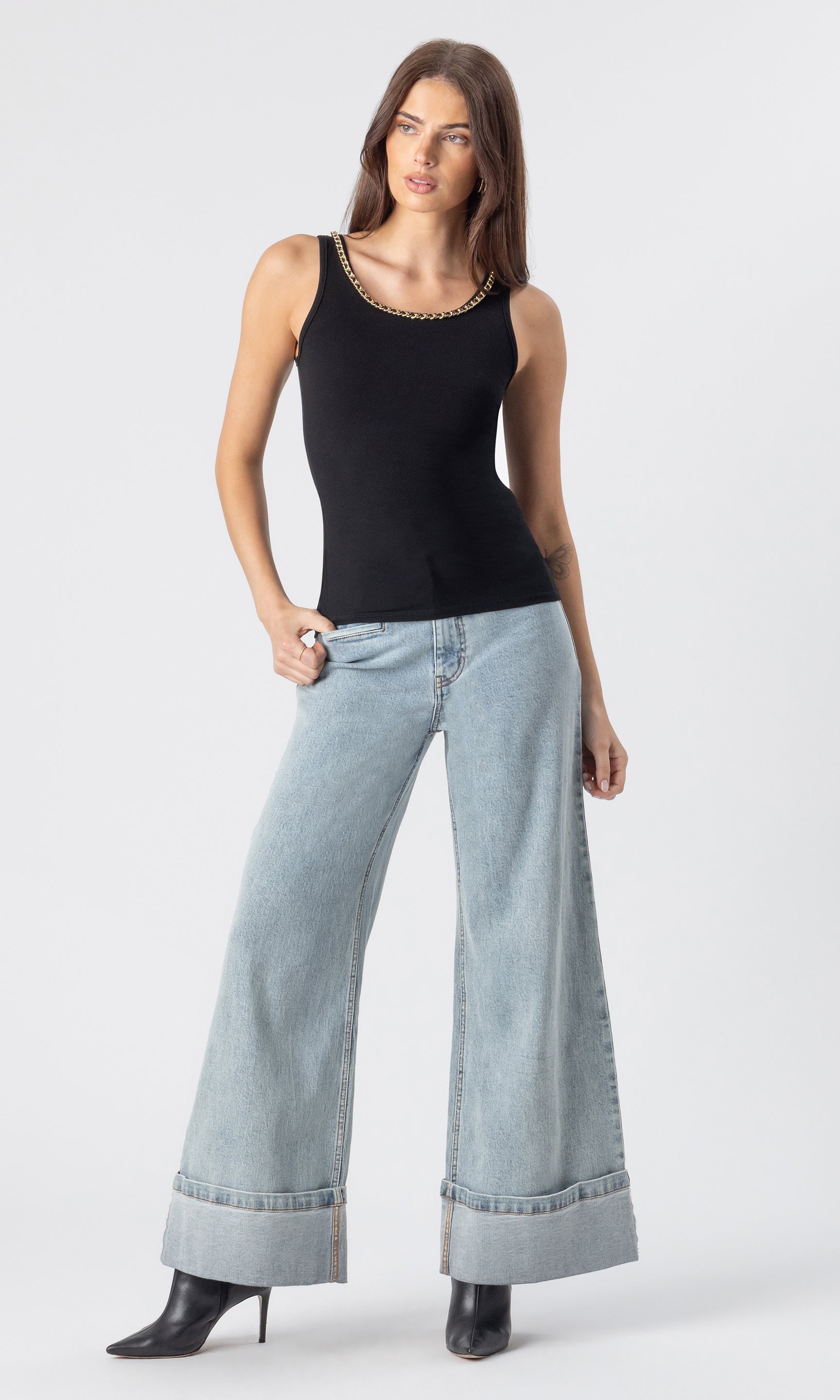 full body image of model wearing the Raquel denim jeans in light blue, paired with a black tank and black heeled booties