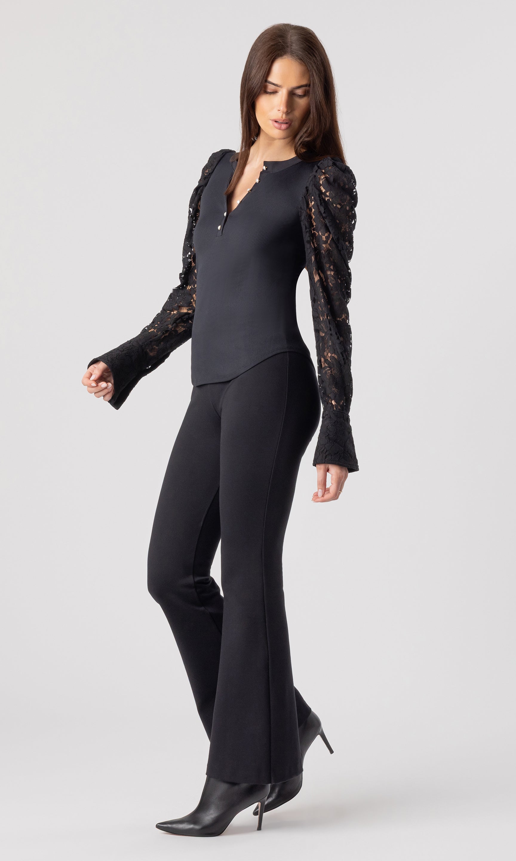 full body side view image of model wearing the Macoy top in black with matching black leggings and black heeled booties