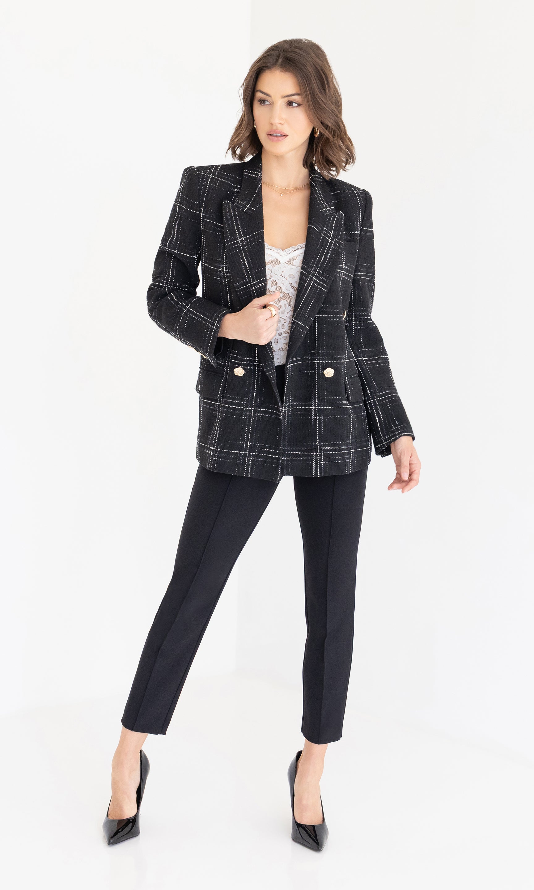 Woman wearing a black and white checkered blazer and black pants on a white background