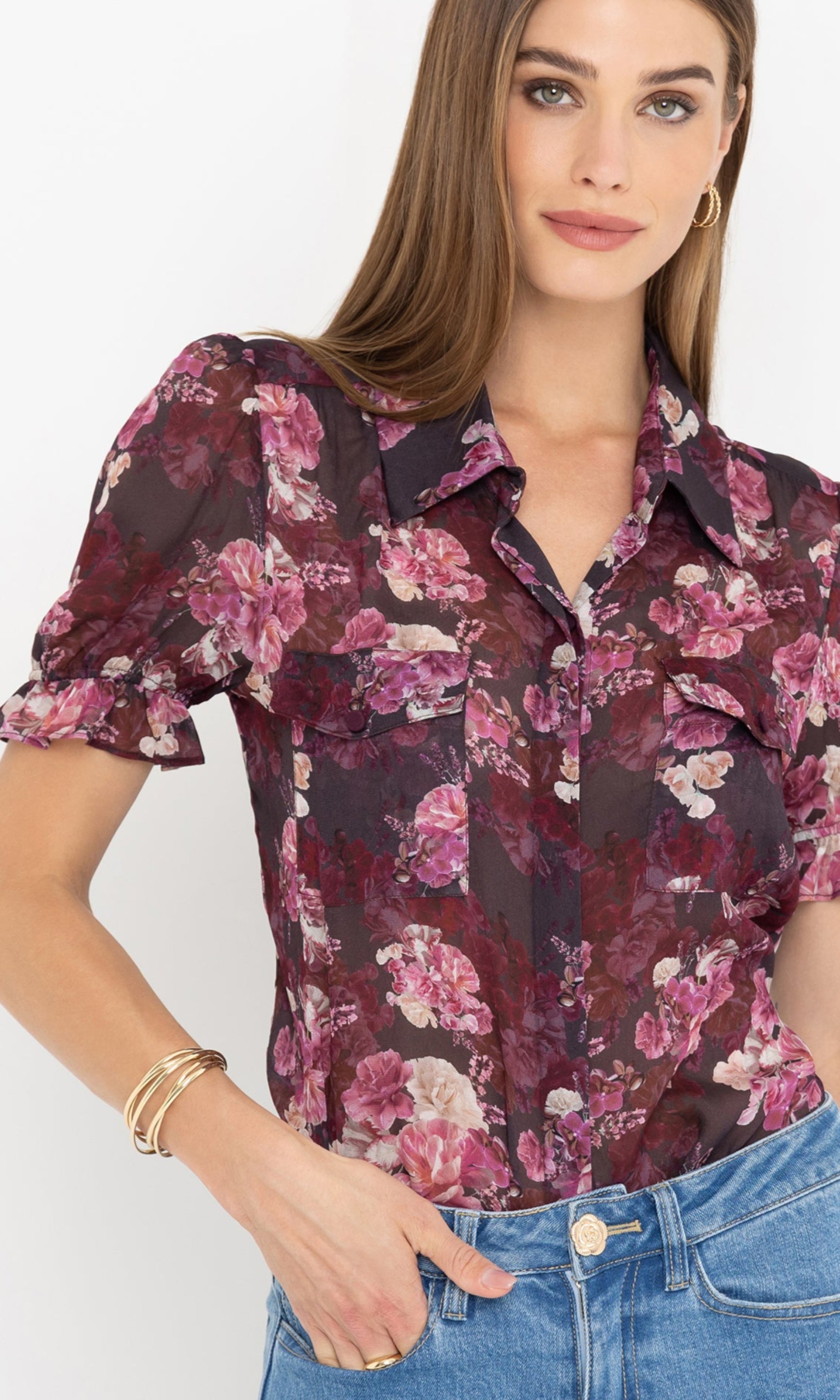 Zoomed in detail image of model wearing a floral blouse and blue jeans against a white background