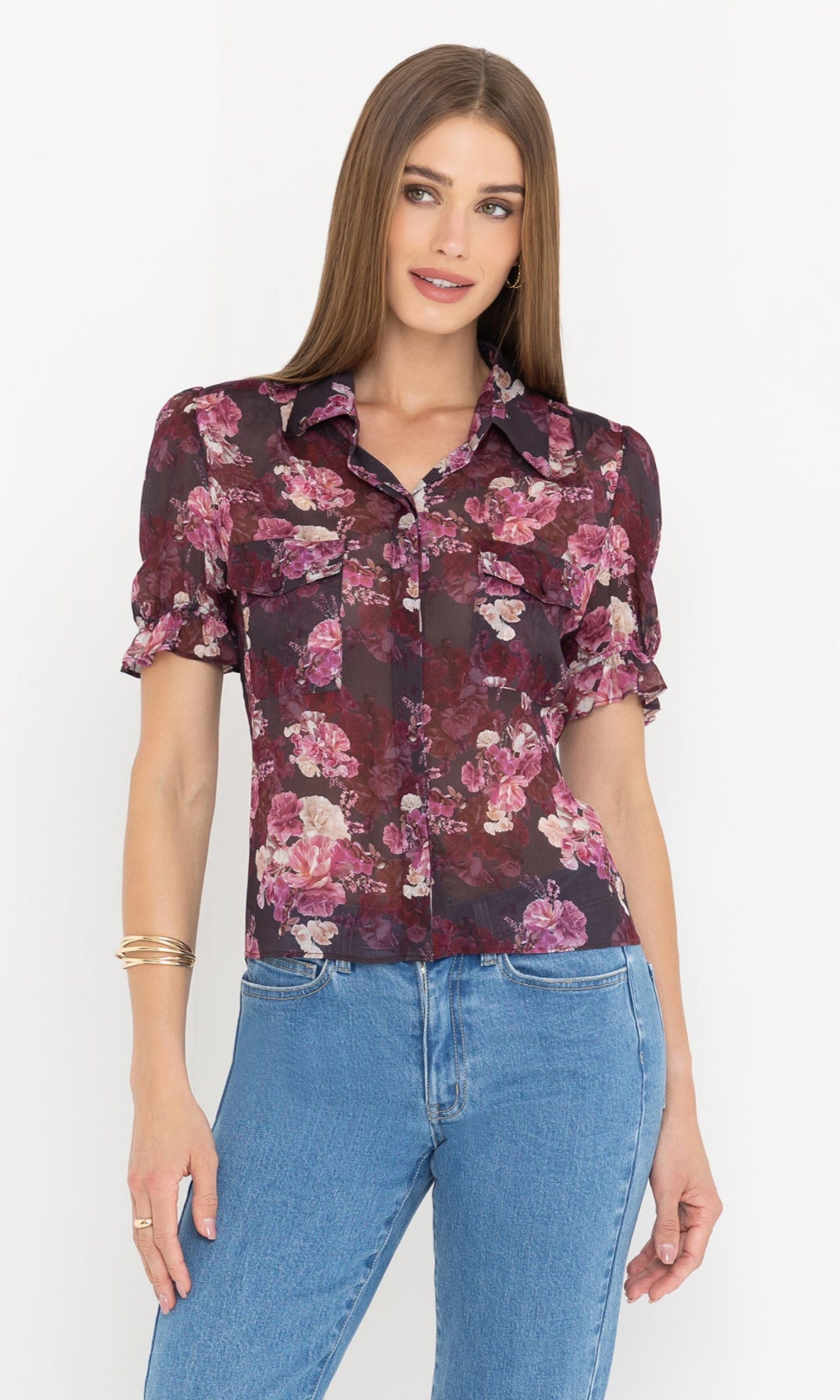 The model wears the Mina Floral Georgette Shirt in a rich floral print with short puff sleeves, paired with light blue jeans, front view.