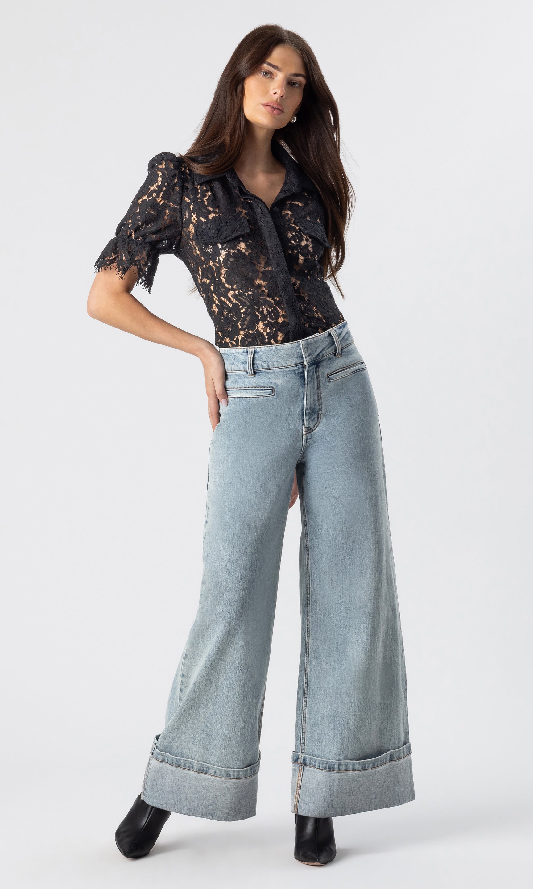 full body image of model wearing the Raquel denim jeans in light blue, paired with a black lace top and black heeled booties