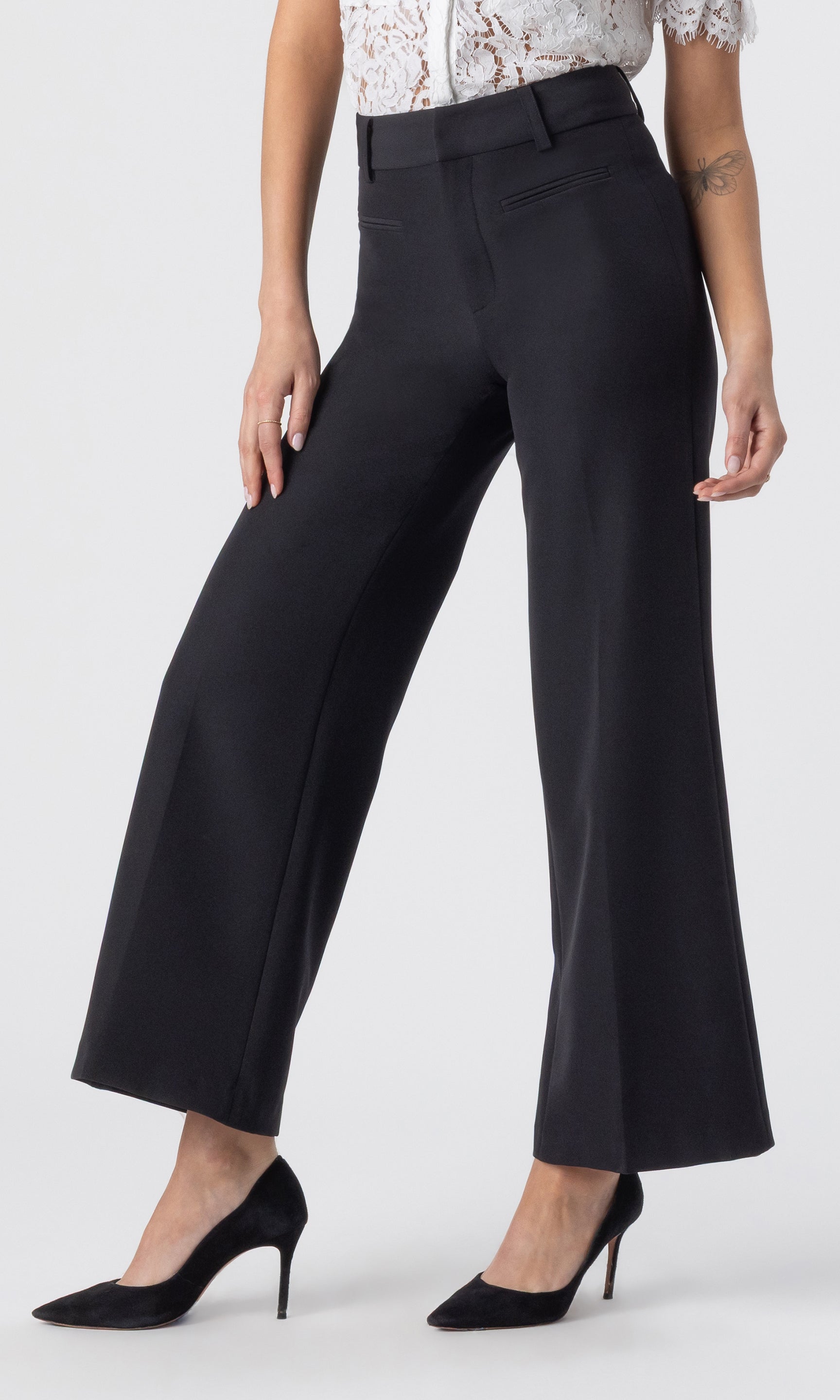 cropped side view image of model wearing a white lace top paired with the Rayne crepe wide-leg pants with black heels