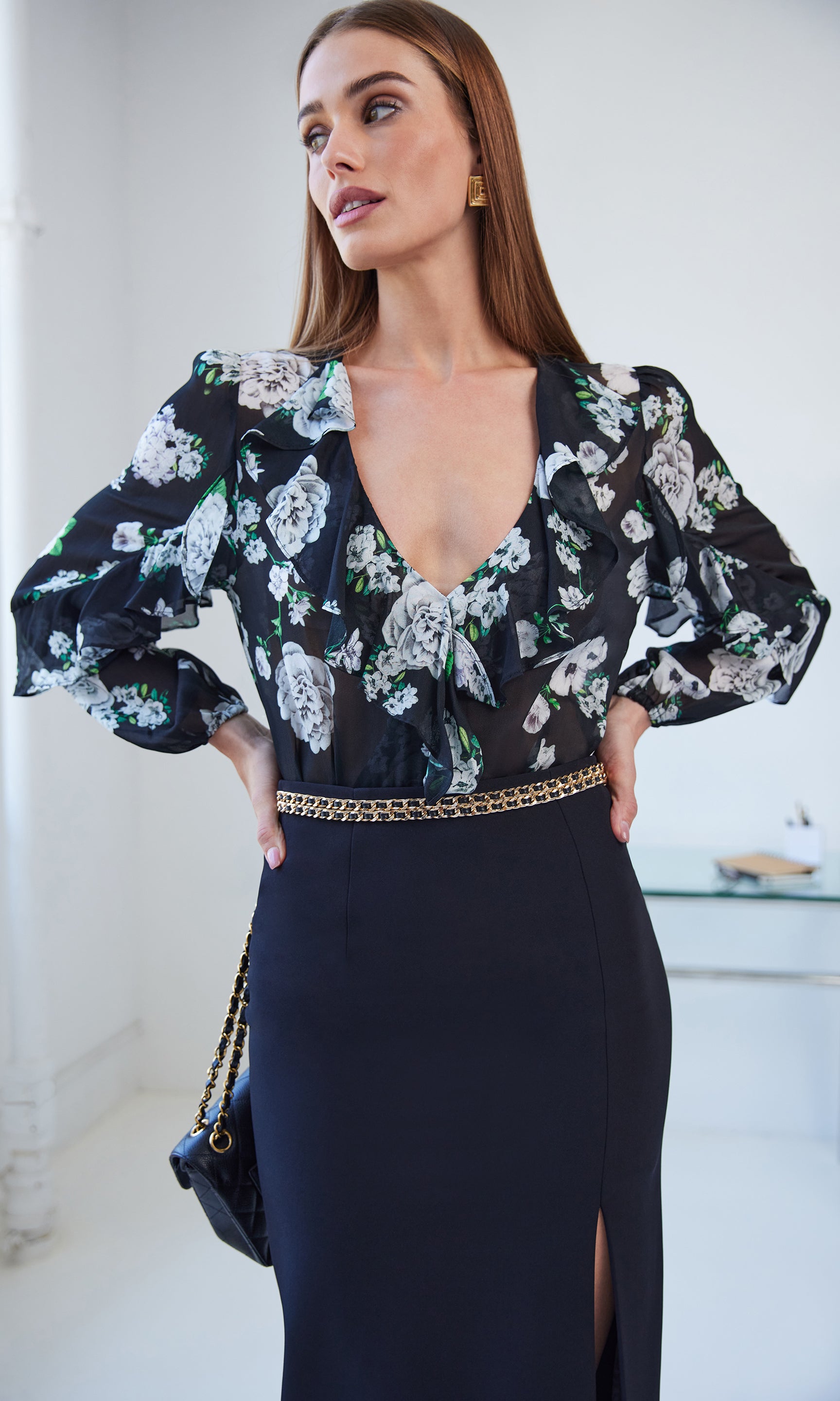 Woman wearing a floral blouse and black skirt with a white background