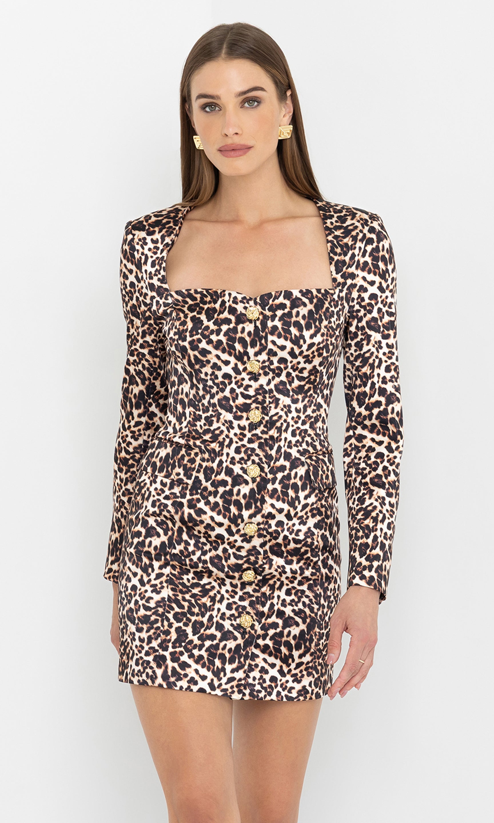 The model wears the Odelia Leo Satin Dress in a front view, highlighting its leopard print pattern and fitted silhouette.