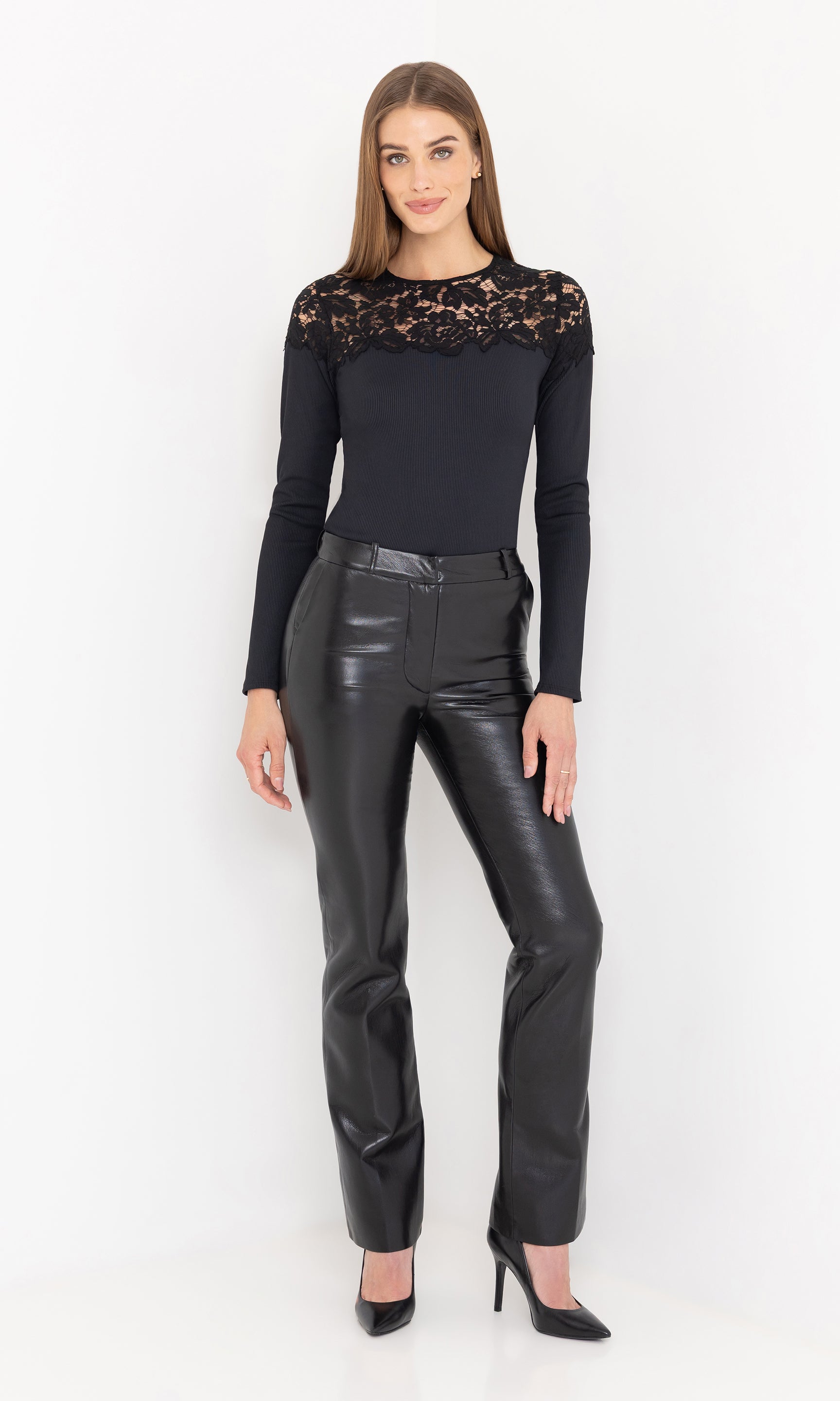 The model in a full front view wearing the pants with a black fitted top and heels.