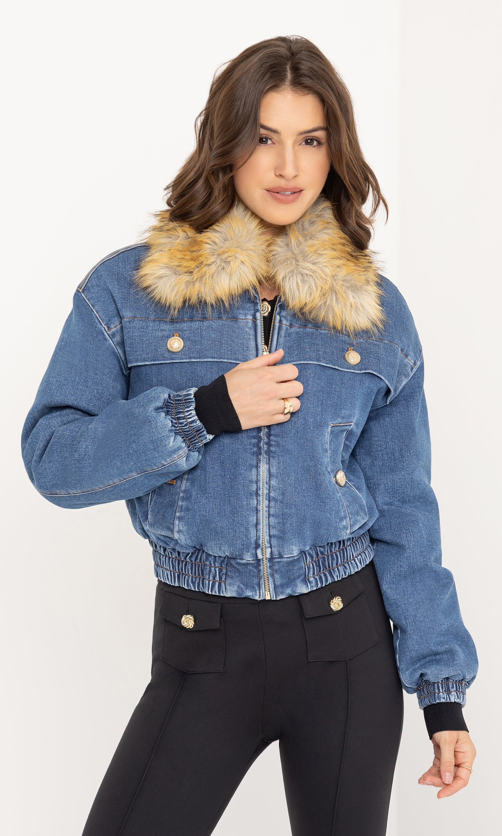 Three-quarter front view of the model smiling in the Paco Denim Bomber with a black buttoned top and black trousers.