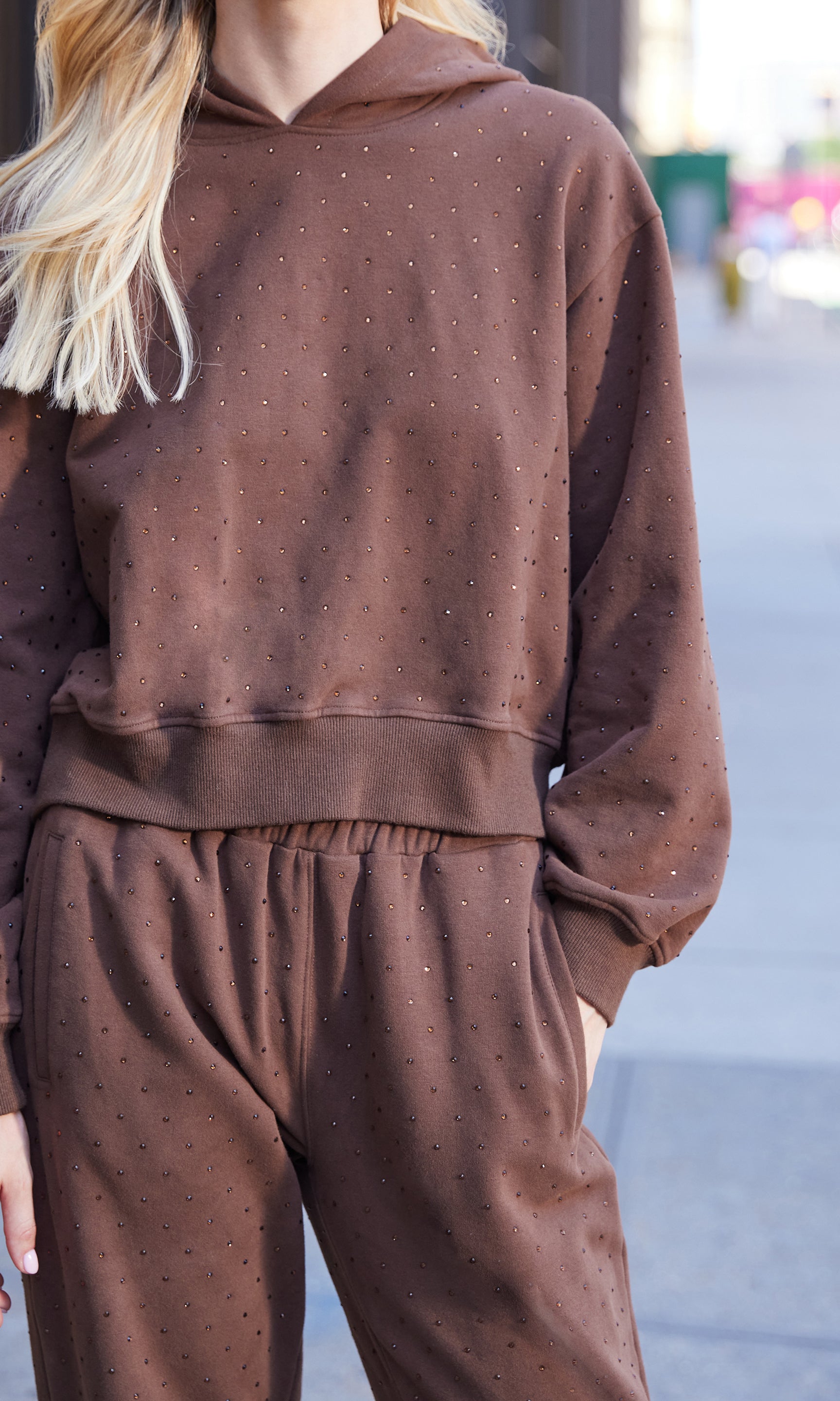 Brown sweatsuit worn by a person on a blurred street background
