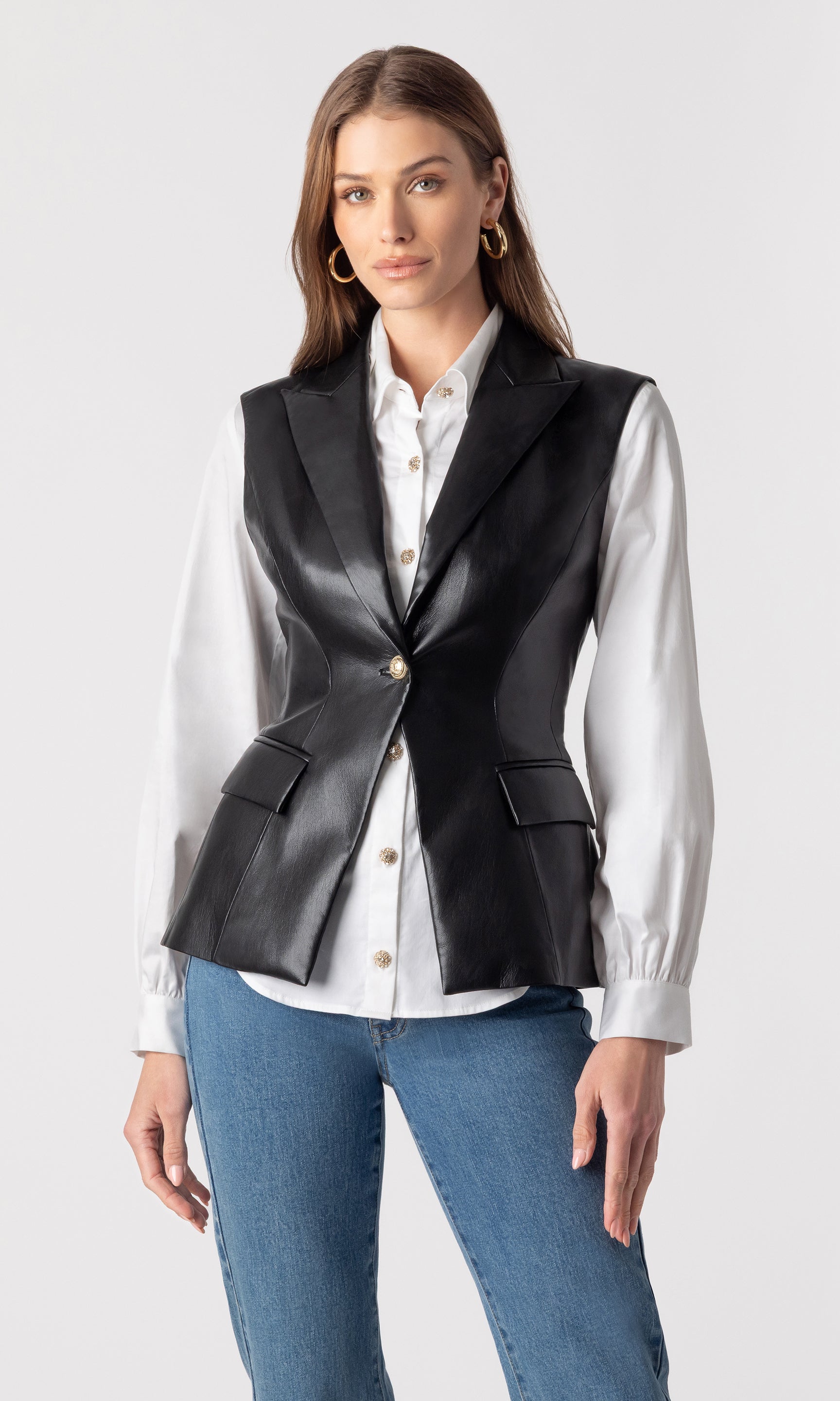 image of model wearing the vegan leather Rialto sleeveless blazer over a white button-down blouse and paired with blue jeans