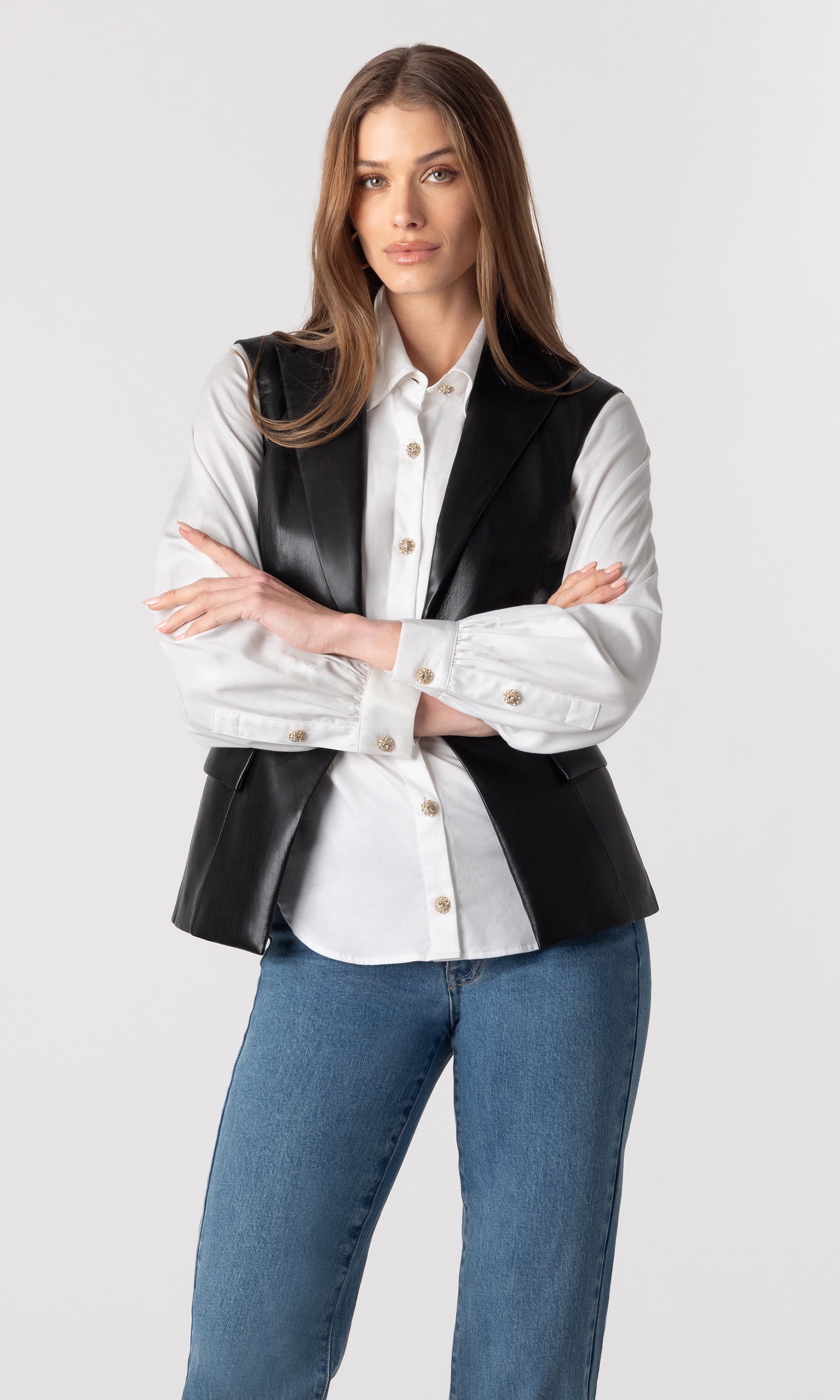 image of model wearing the vegan leather Rialto sleeveless blazer un-buttoned over a white button-down blouse and paired with blue jeans