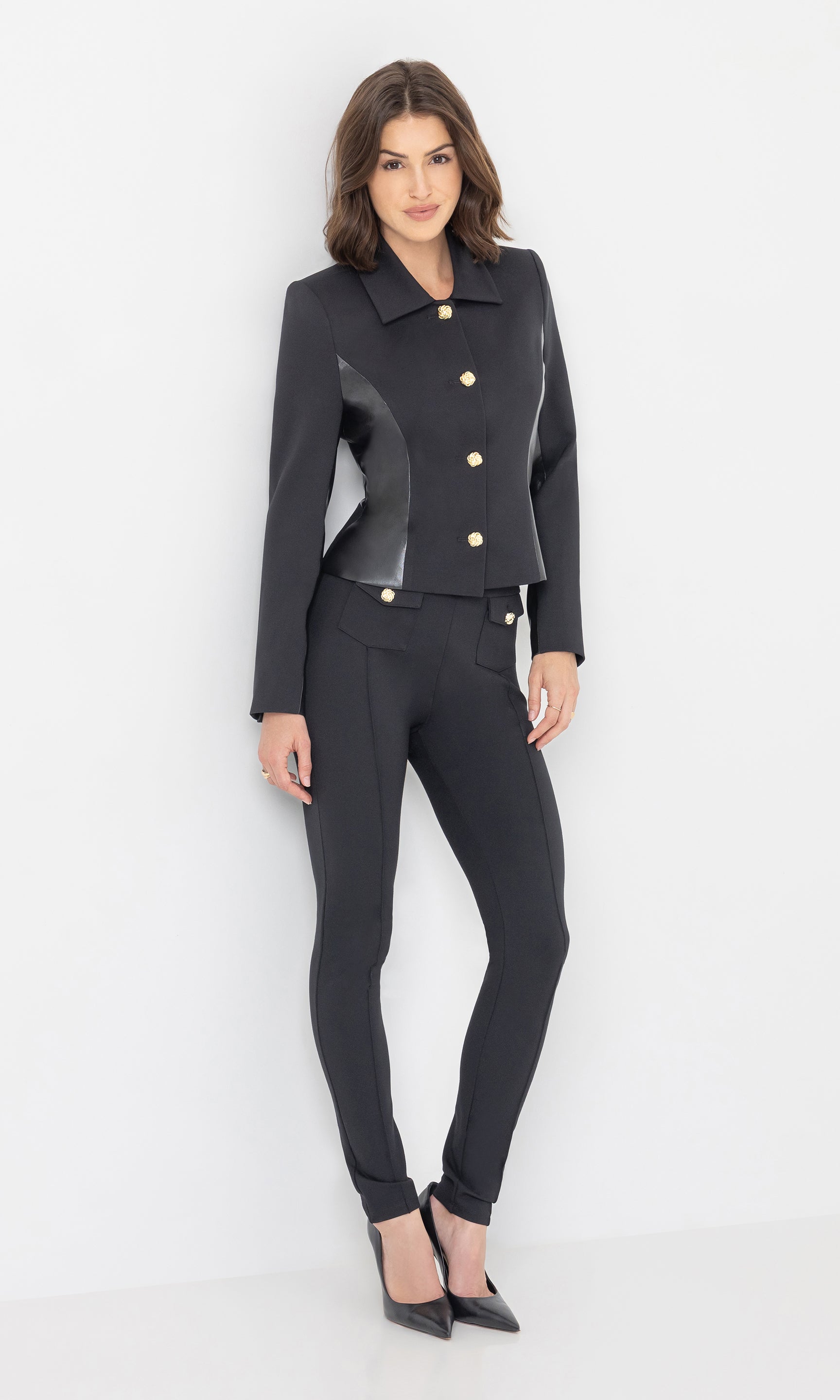 Full body front view of the model wearing the Robby Vegan Leather Combo Ponte Jacket in black, paired with matching black pants and heels.