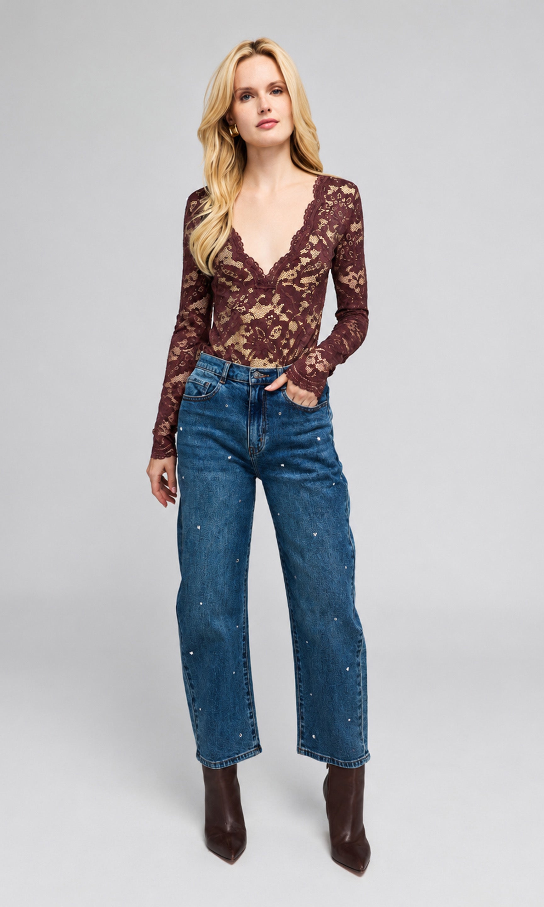 Model wearing a dark brown lace long-sleeve top and blue denim jeans with rhinestone embellishments.