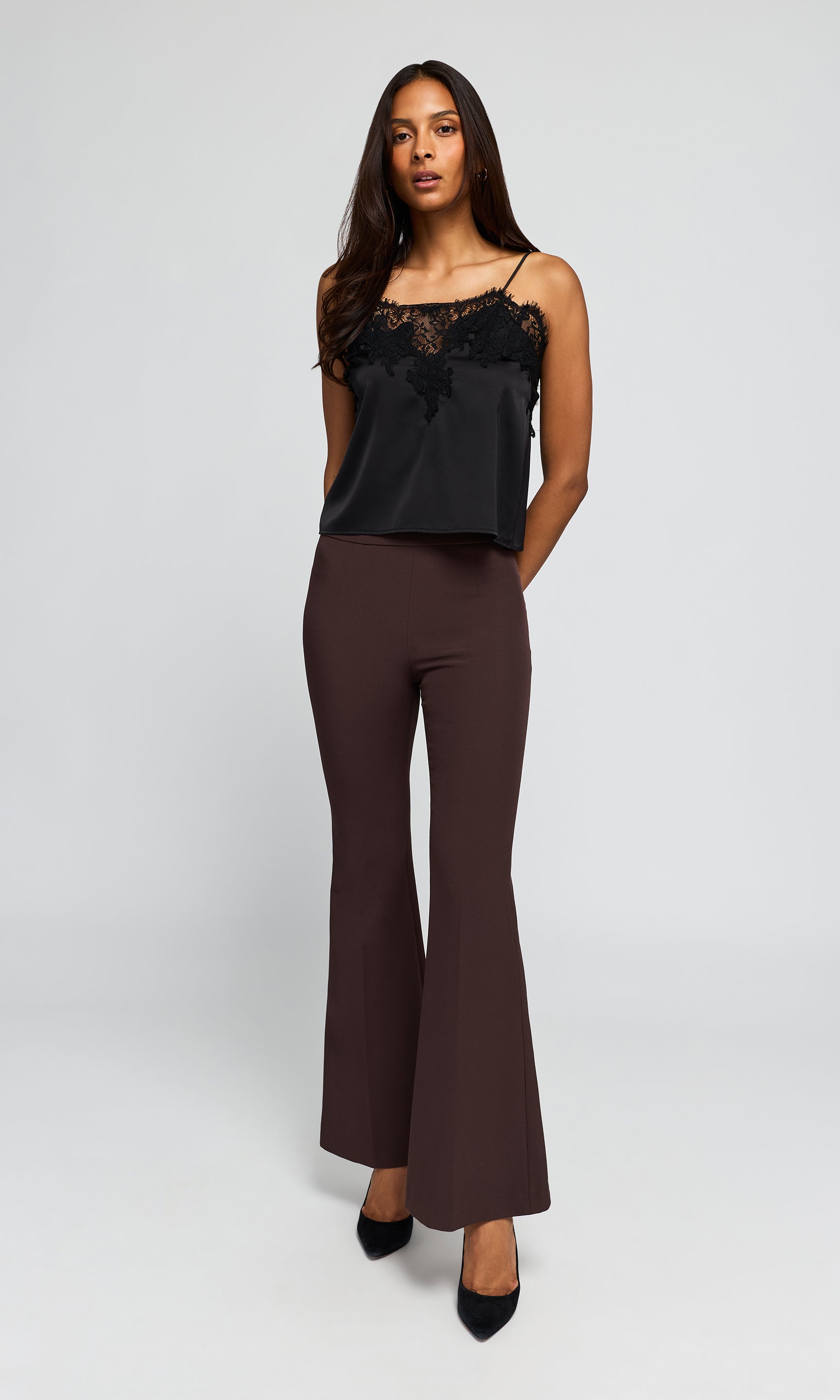 A woman modeling a black lace-trimmed camisole top and dark brown flared pants.