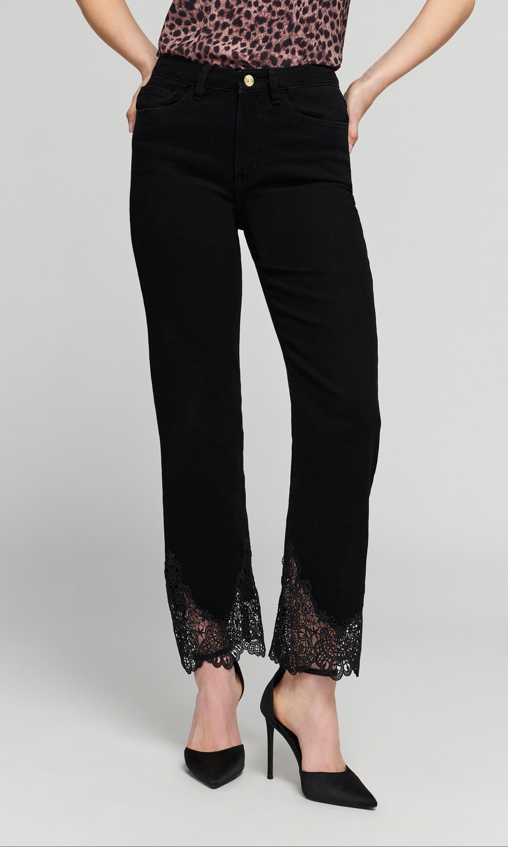 Model wearing black cropped  jeans with black lace trim at the hem, shown on a model on a plain background.