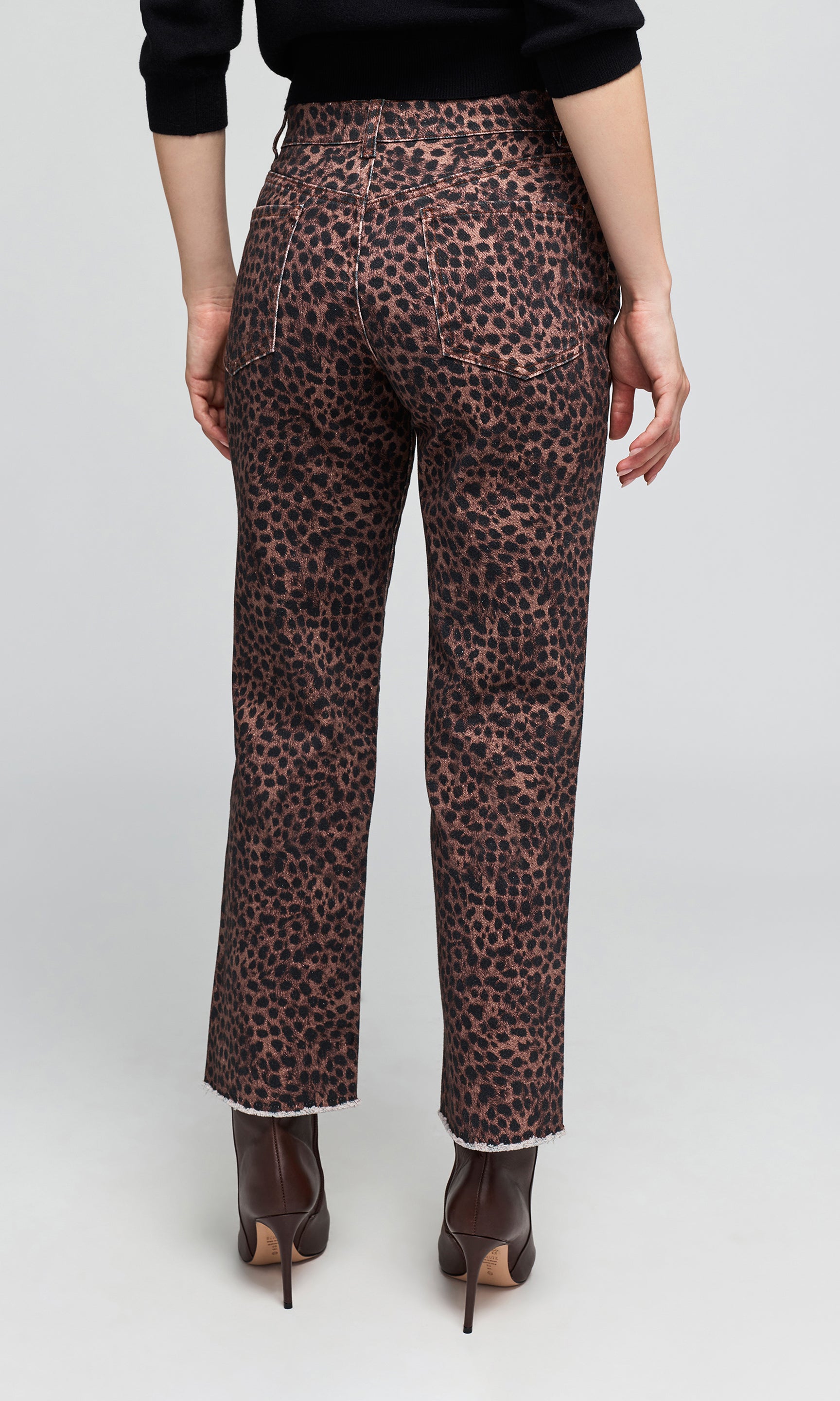Back view of model wearing high-waisted leopard-print trousers in brown and black, paired with dark brown pointed-toe ankle boots.