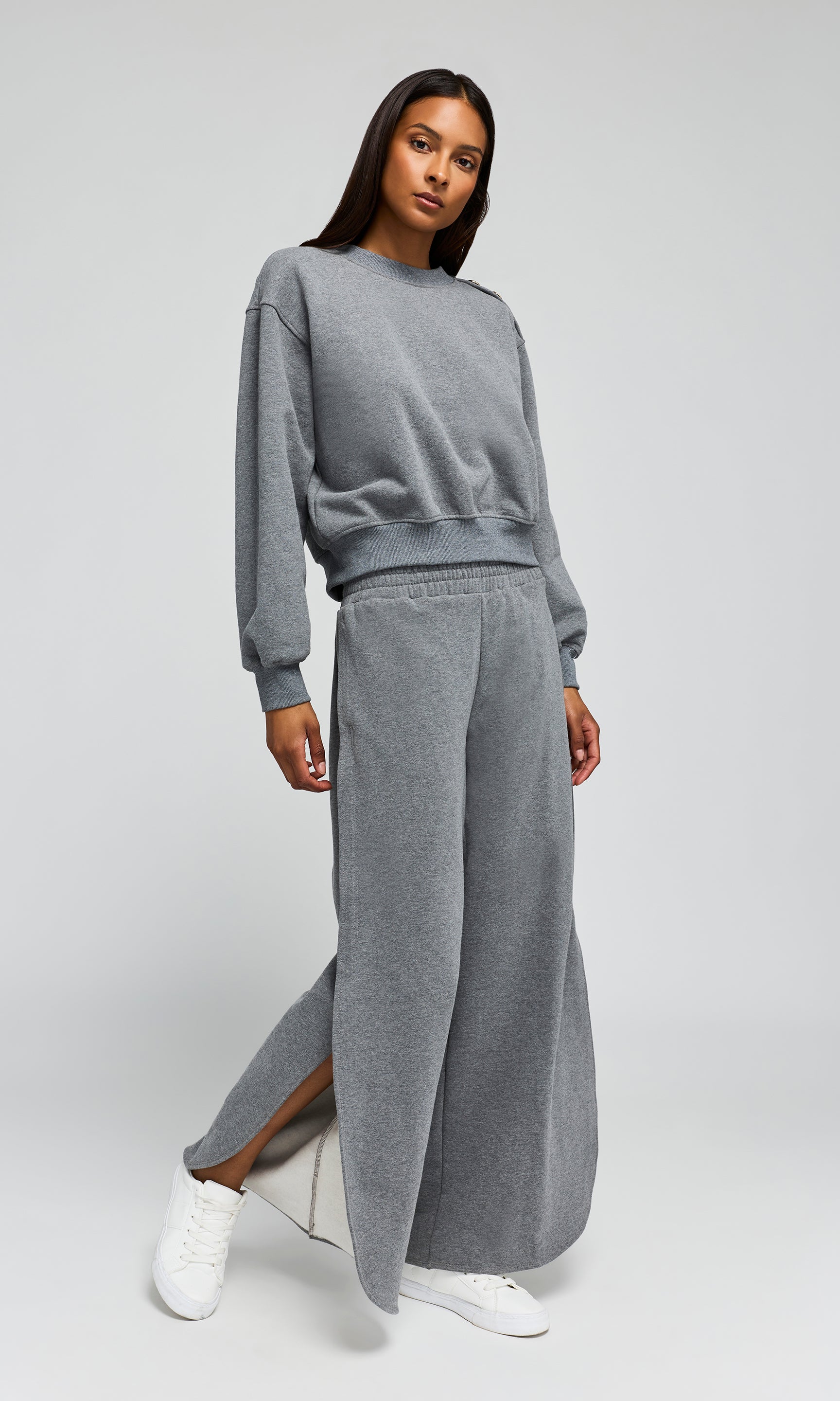 Person wearing a gray sweatshirt and wide-leg pants on a white background