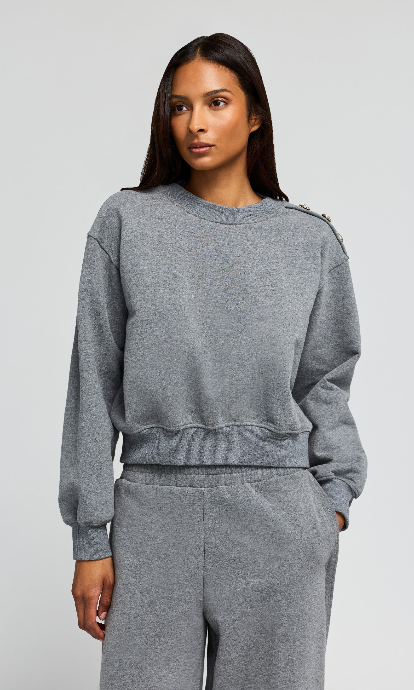 Woman wearing a gray sweatshirt and pants on a light gray background