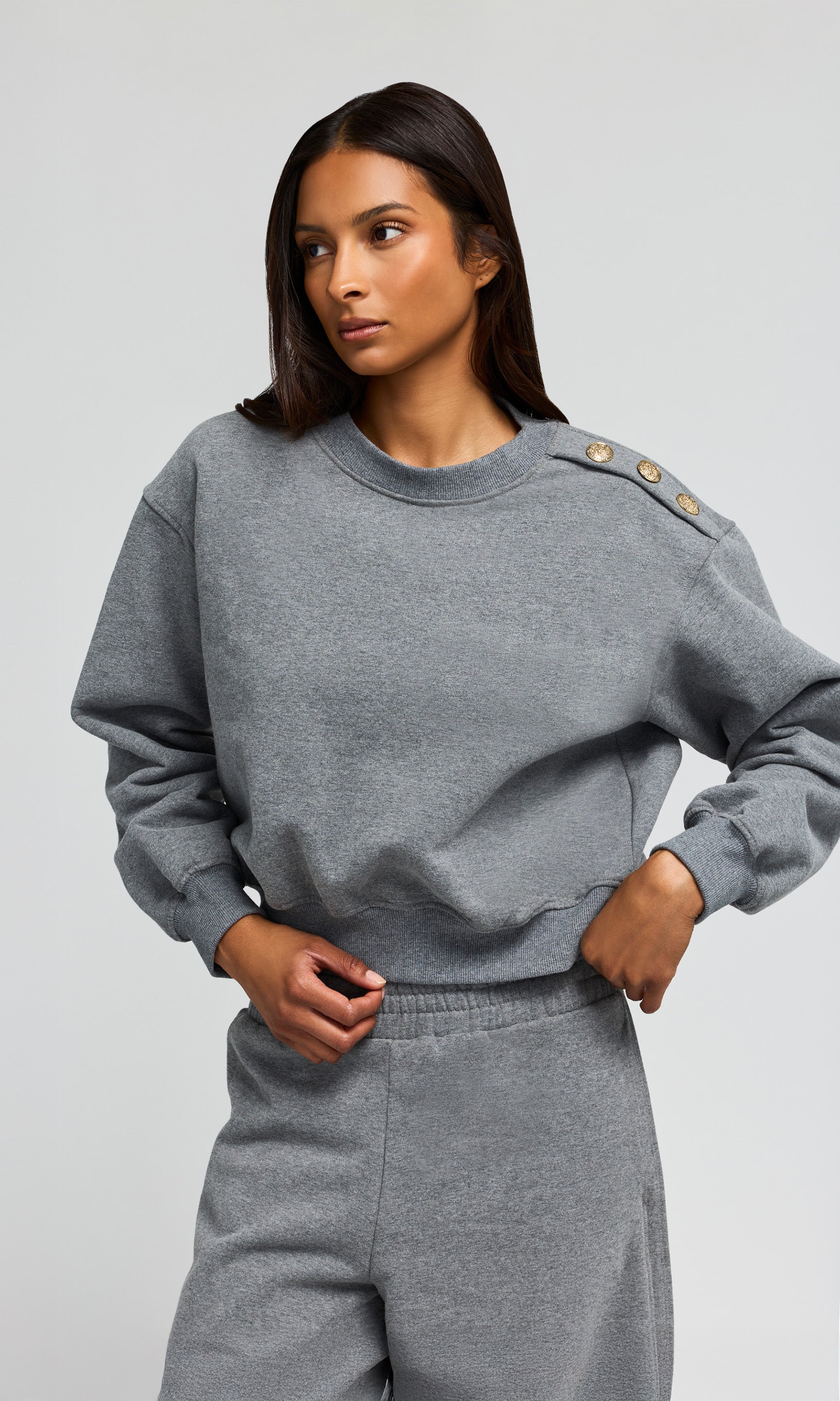Woman wearing a gray sweatshirt and pants on a light gray background