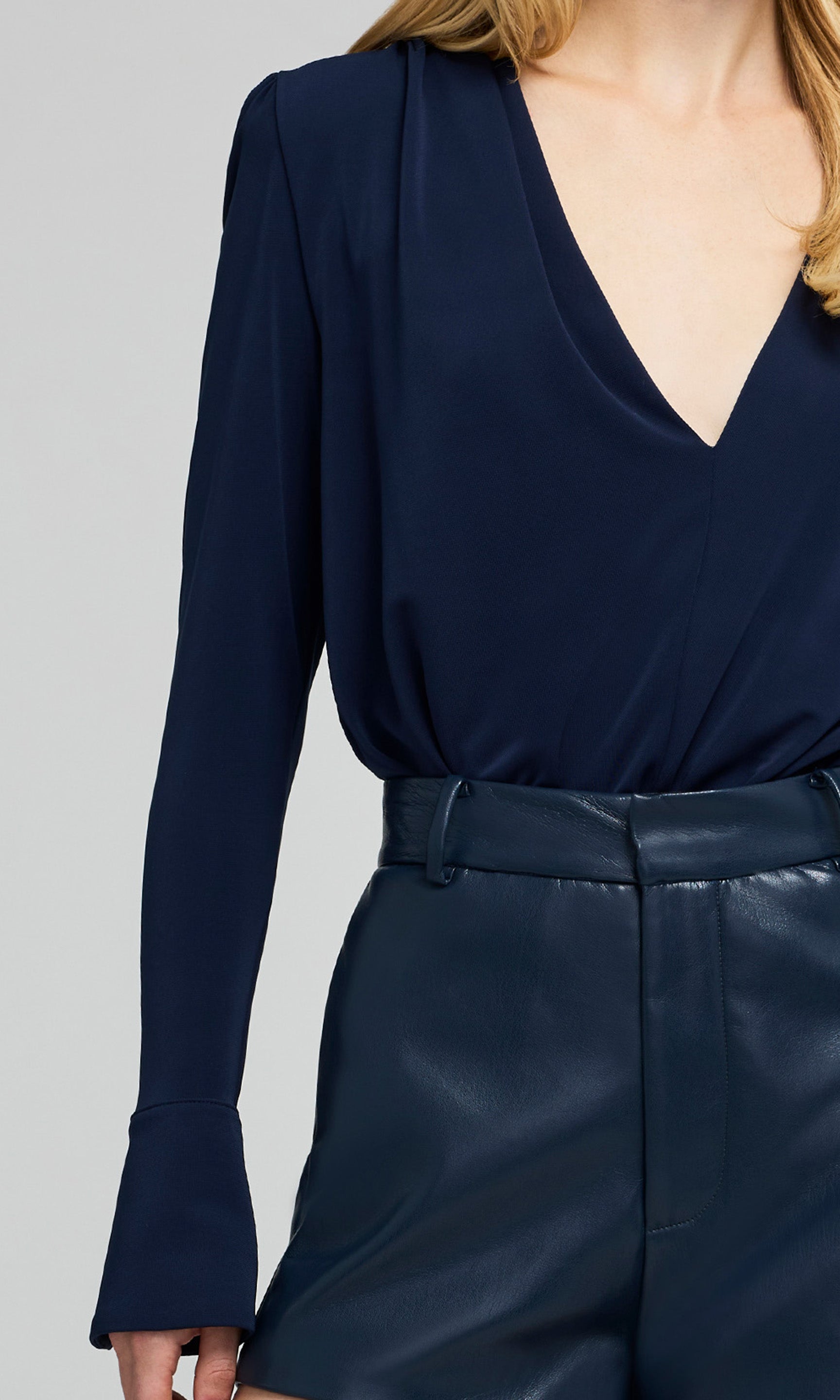 Close-up of navy blue long-sleeve top worn by a person on a gray background