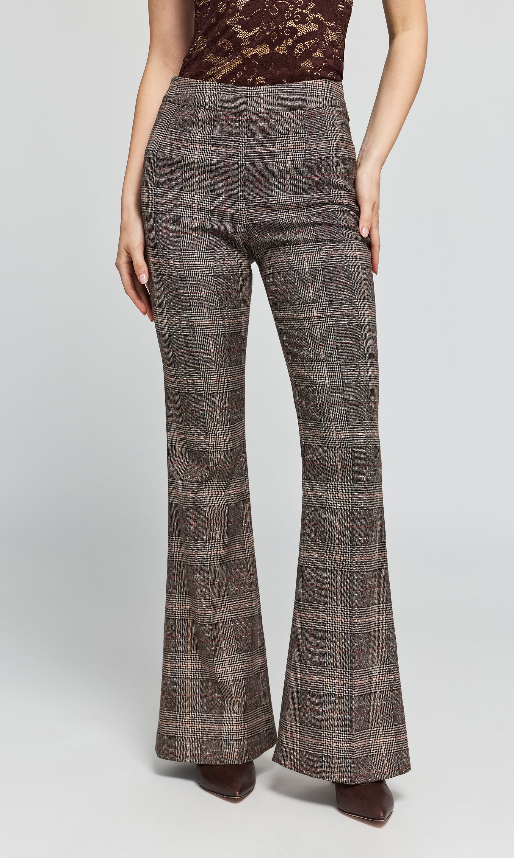 Model wearing a pair of brown and gray plaid flare pants with a lace top, on a plain background.