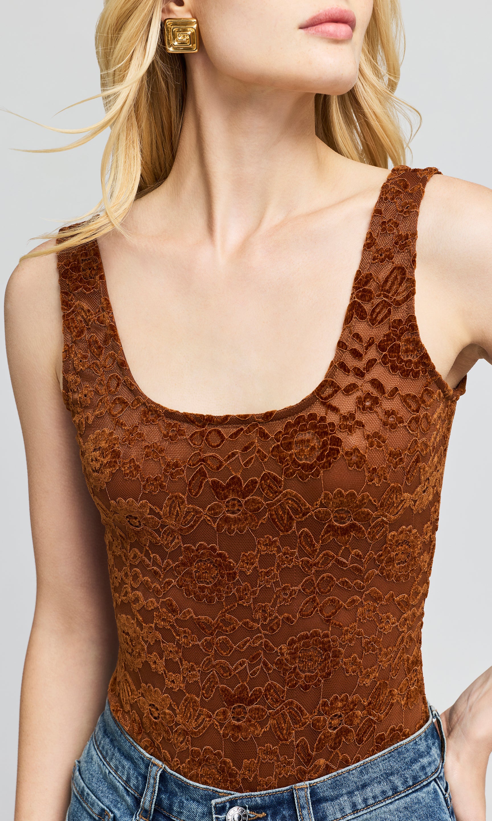 Close-up of a brown lace sleeveless top with a scoop neckline.background.