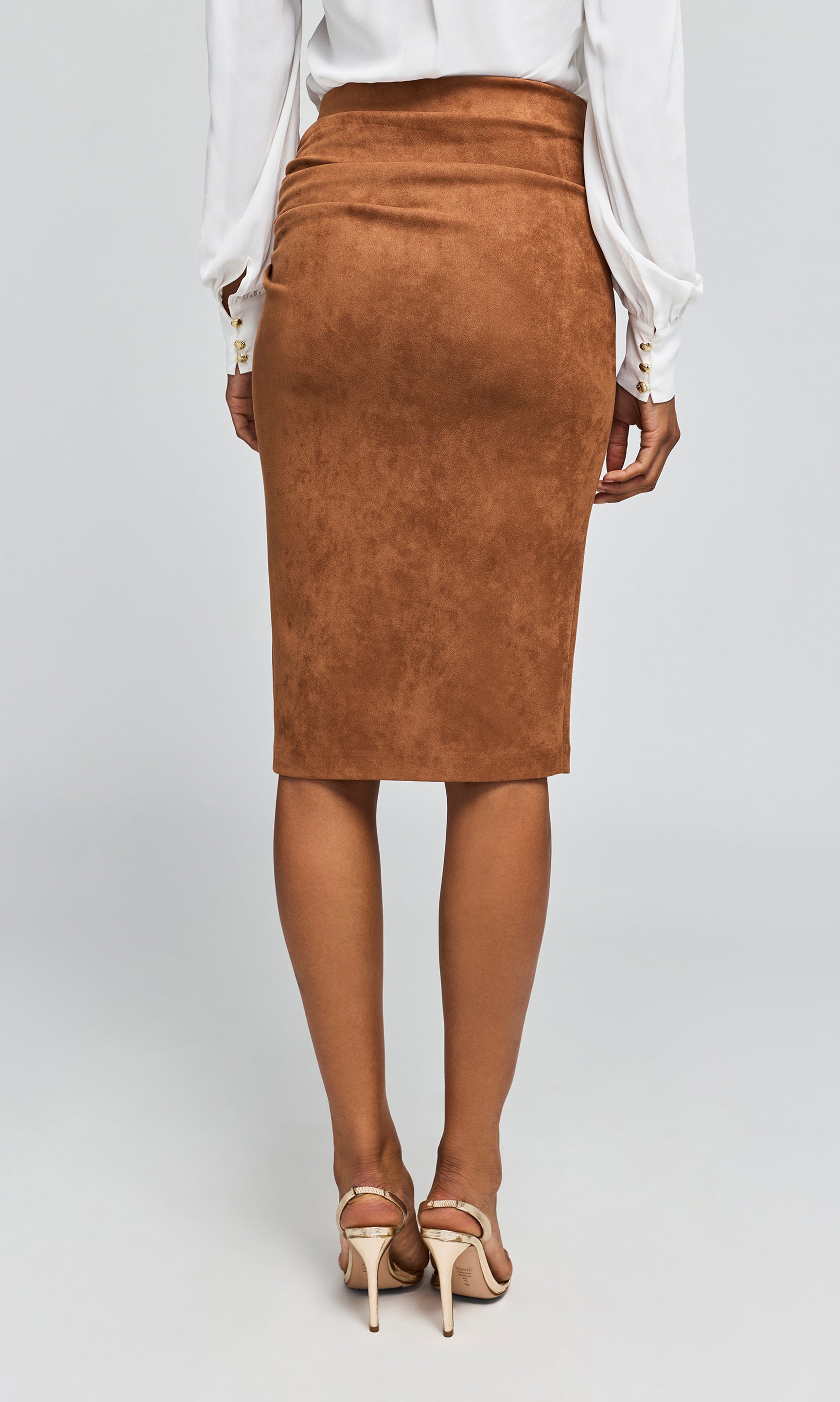Back view of model wearing a ruched brown faux-suede pencil skirt with an asymmetrical side slit.