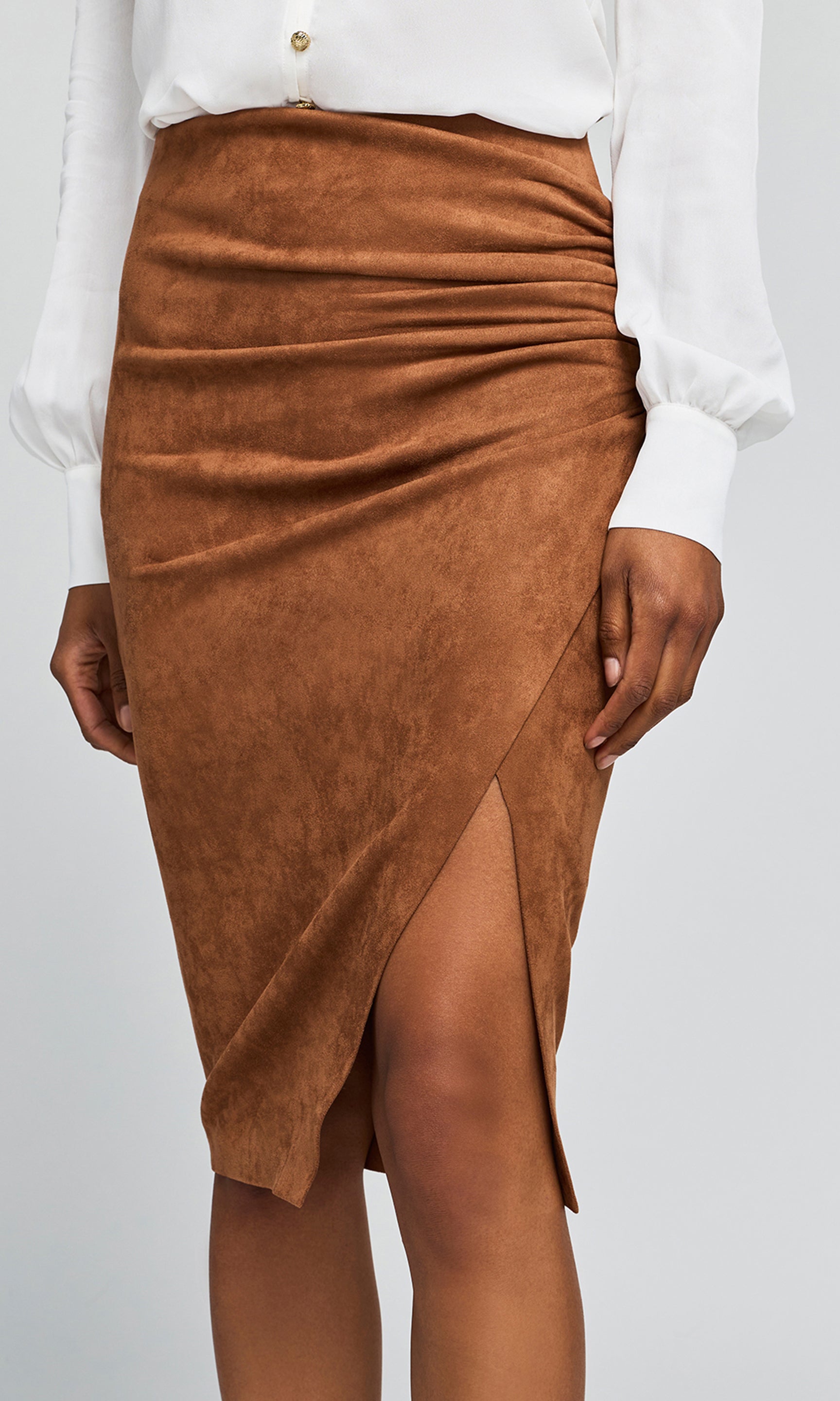 Close-up of brown faux-suede ruched wrap skirt with a thigh-high slit, on a plain background.
