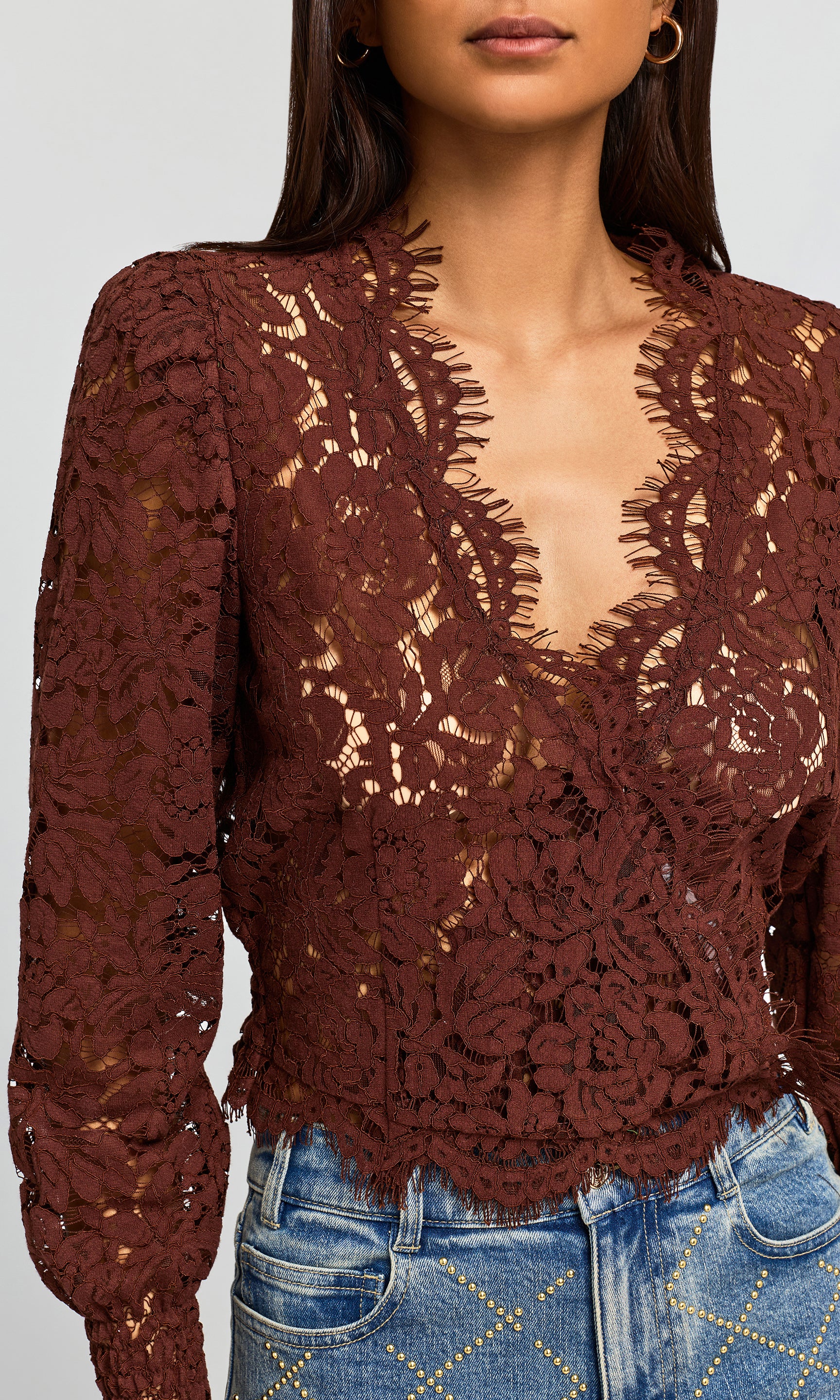 Close-up of a deep reddish-brown color, paired with blue jeans against a light gray background.