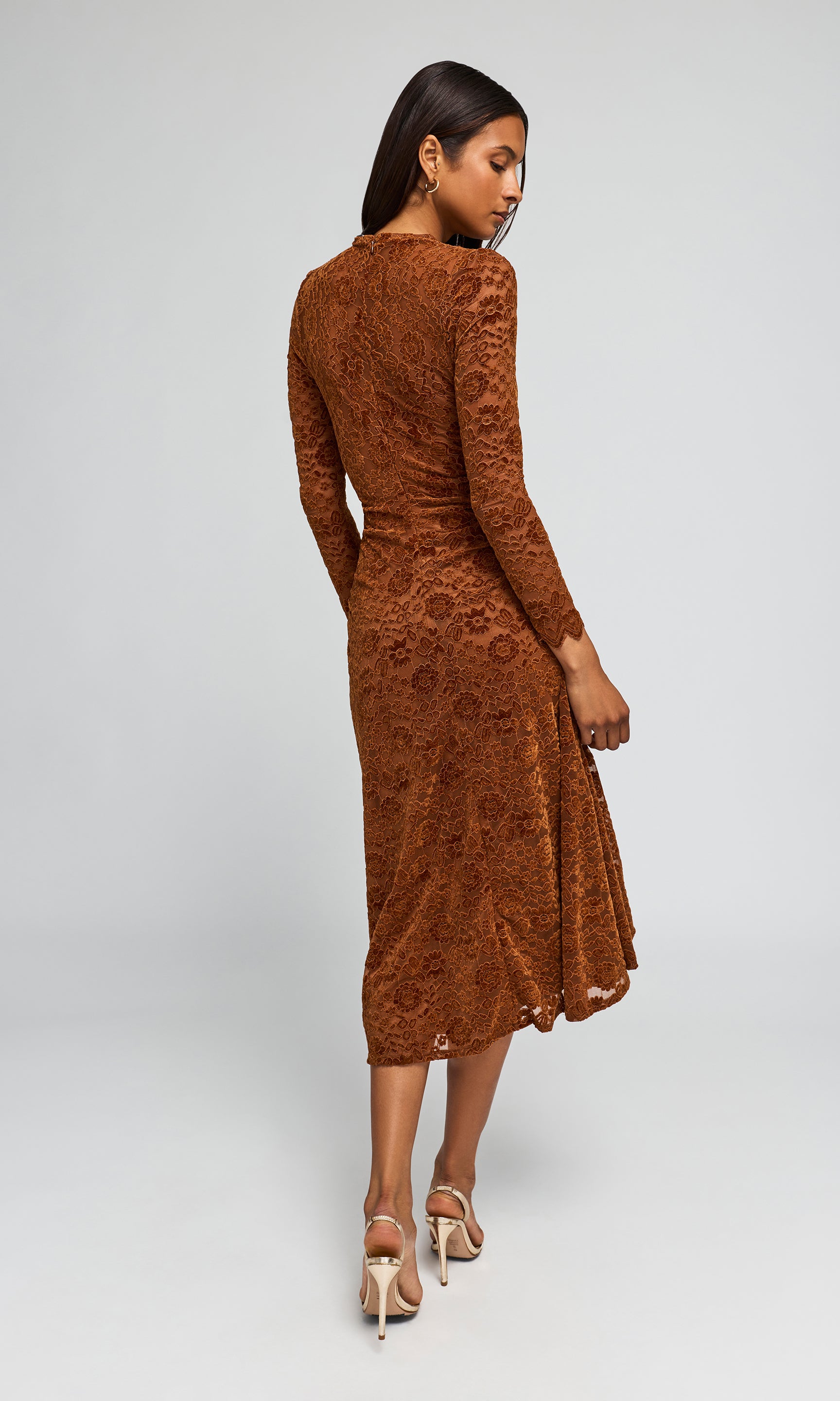 Back view of woman modeling a rust-brown long-sleeve lace midi dress with a high-low hem.