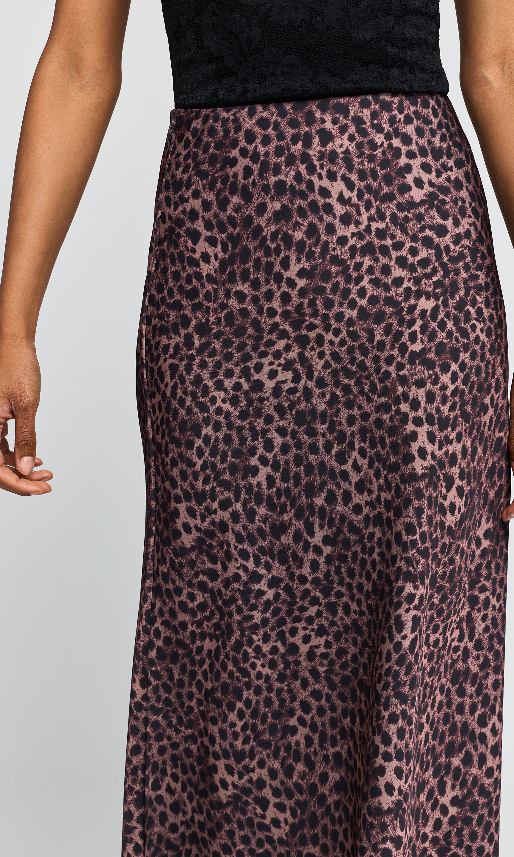 Close-up of a model wearing a leopard print maxi skirt, paired with a black top, against a light gray background.