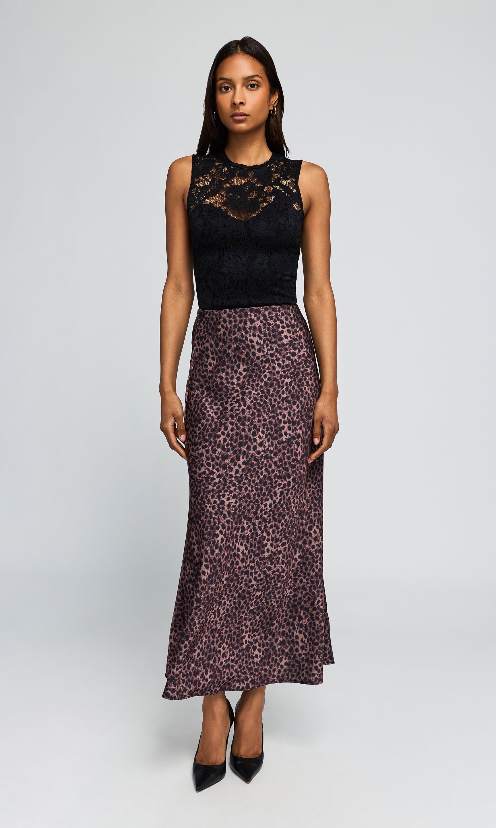 Model wearing a sleeveless black lace top and a leopard-print skirt, paired with black pointed-toe heels.
