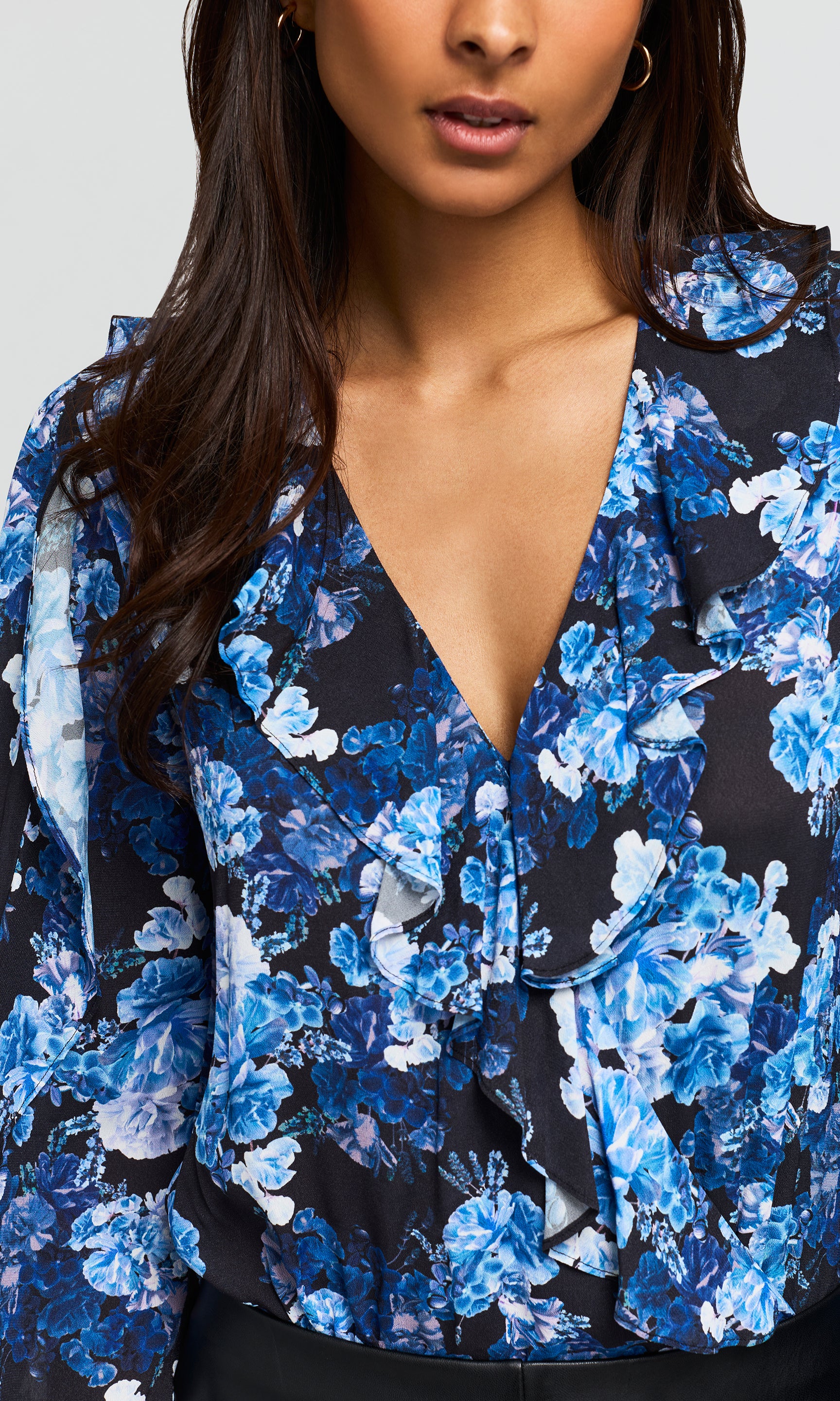 Close-up of a blue and black floral print blouse with a ruffled V-neckline.