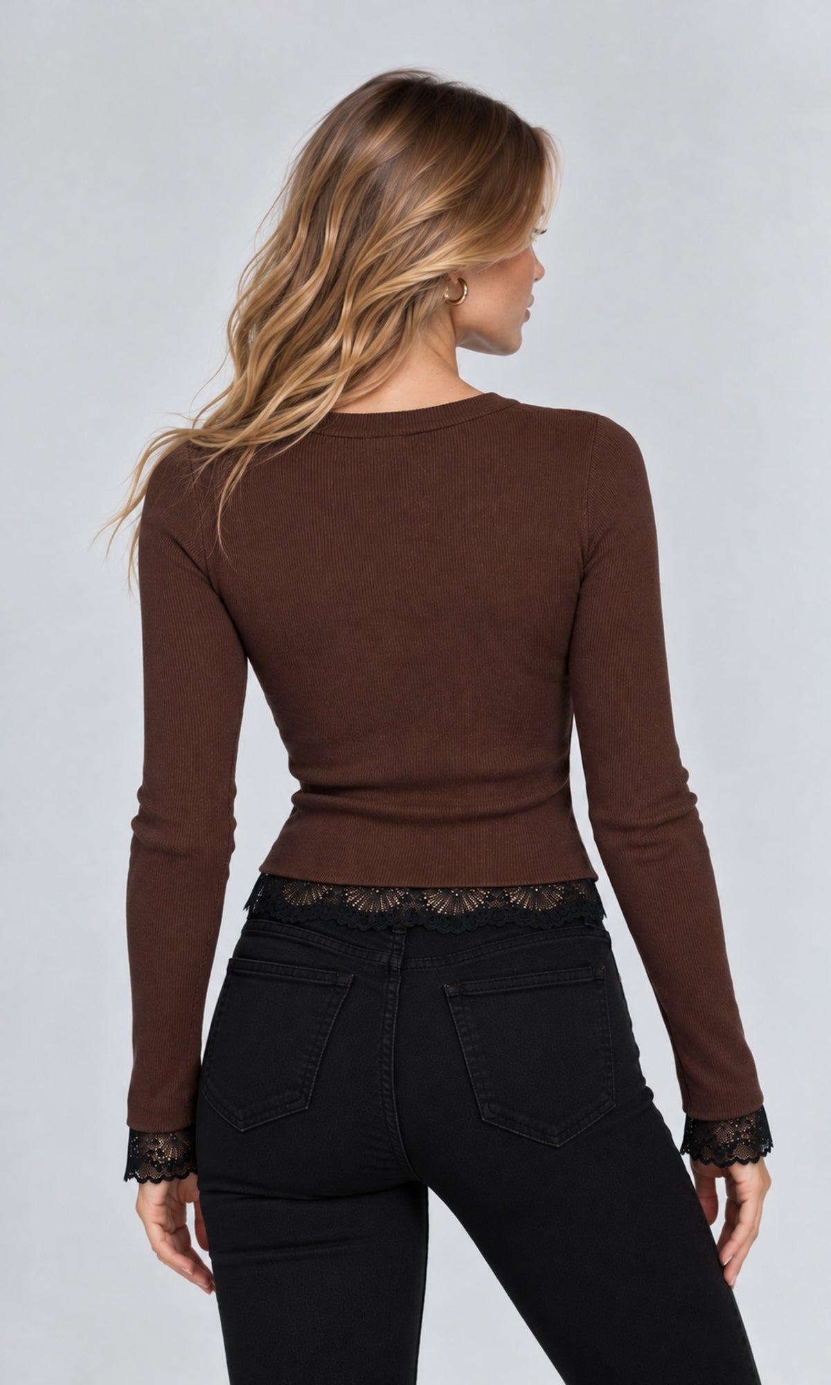 Back view of model wearing a fitted long-sleeve brown top with black jeans and lace trim at the cuffs and waist.