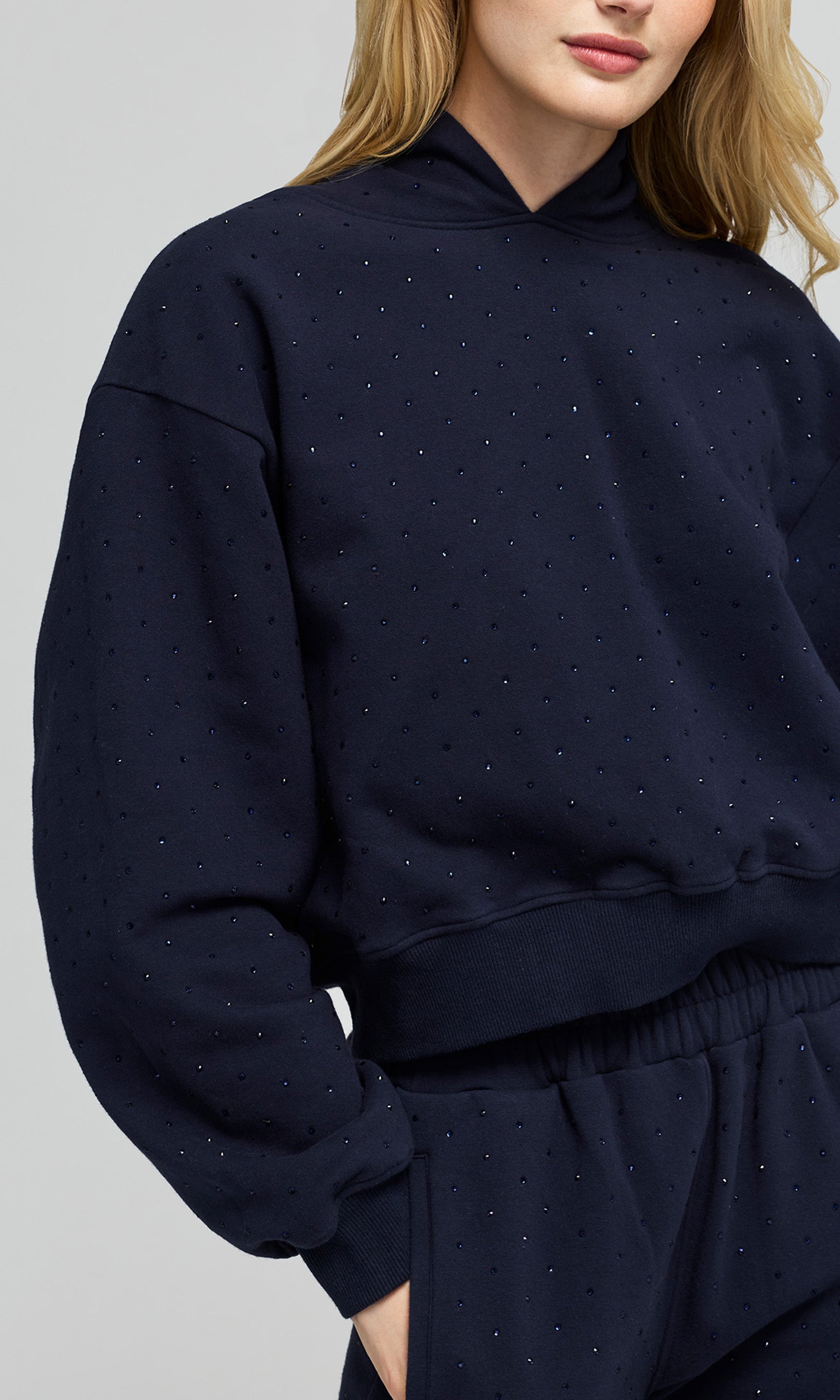 Close-up of a navy blue sweatshirt with crystal embellishments on a plain background.