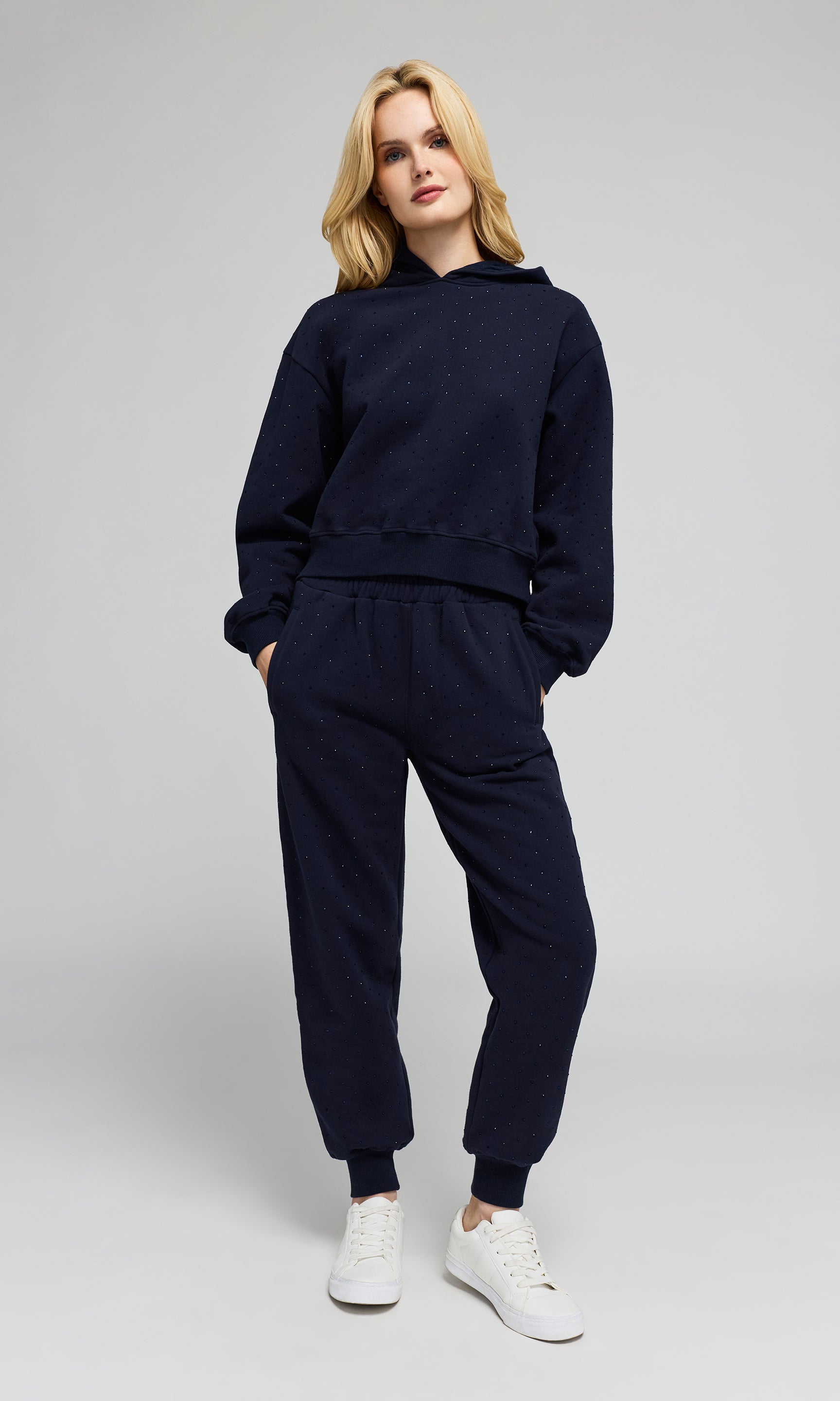 Model wearing a matching navy blue sweatshirt and jogger pants set with crystal embellishments on a plain background.