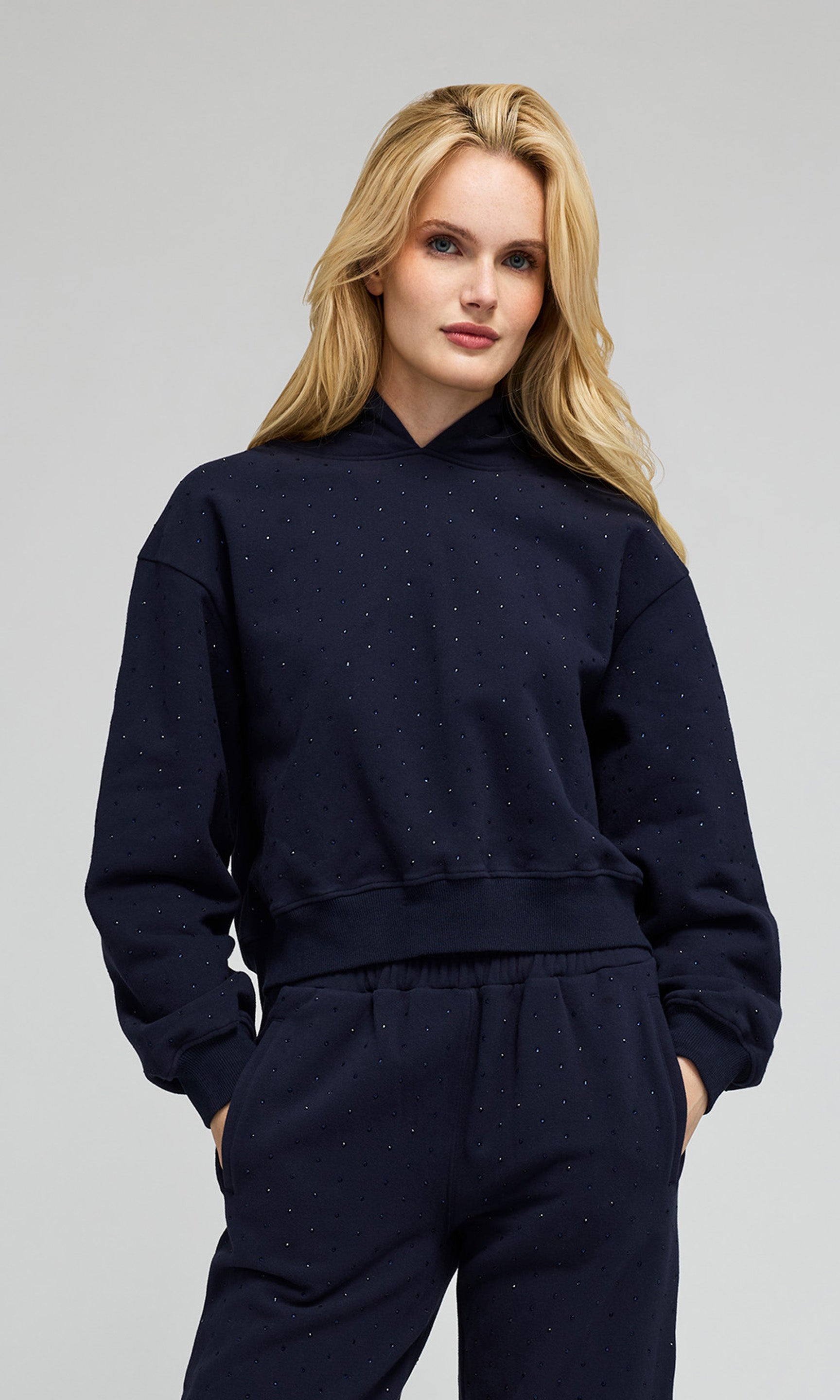 Model wearing a navy hoodie sweatshirt and matching sweatpants, with crystal embellishments on a plain background.